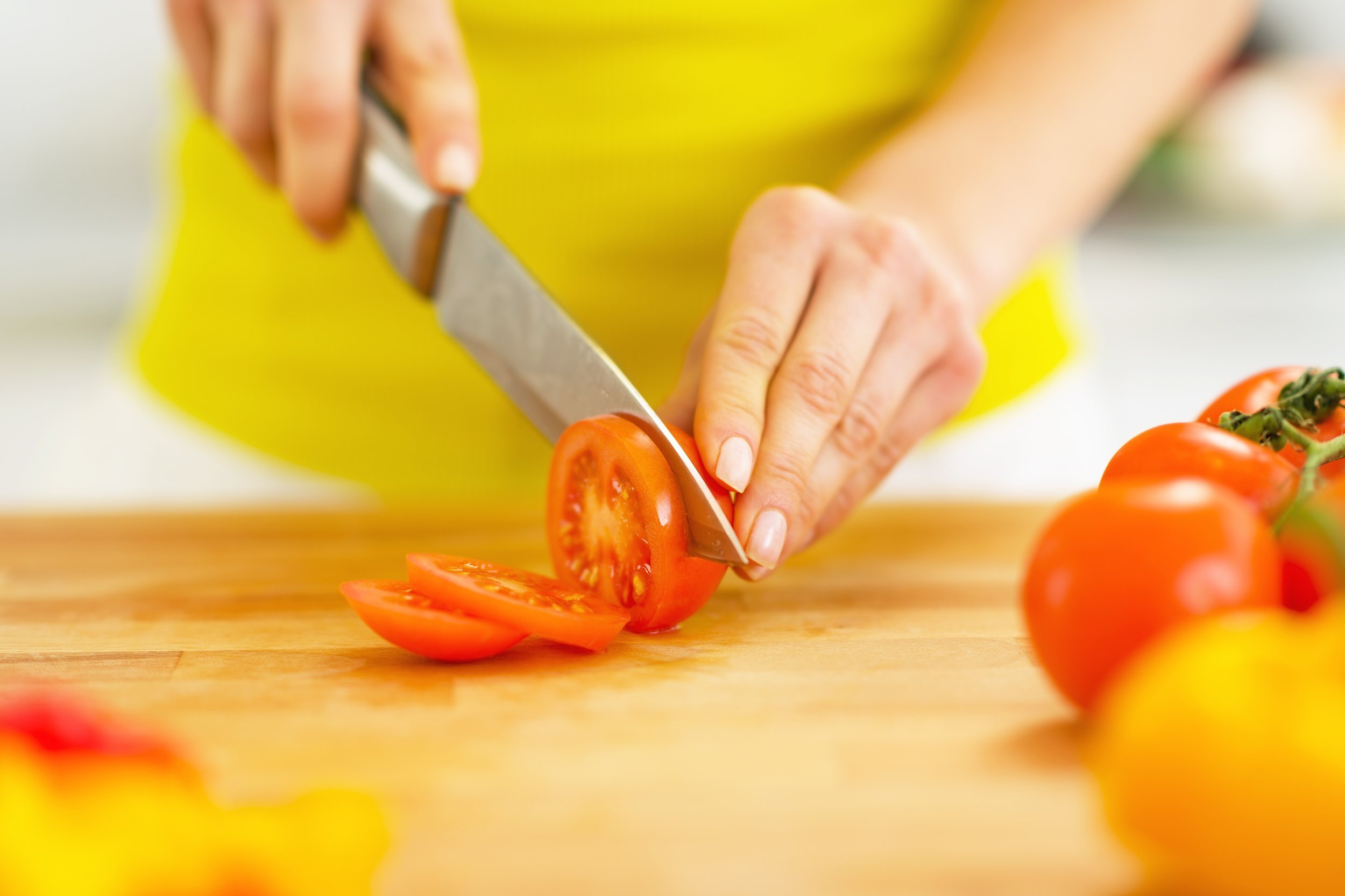woman's hand cutting tomato