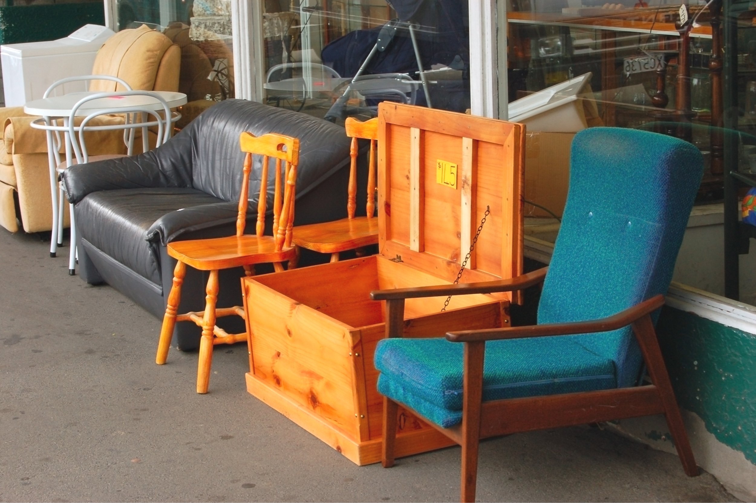 Second-hand furniture on display on sidewalk.
