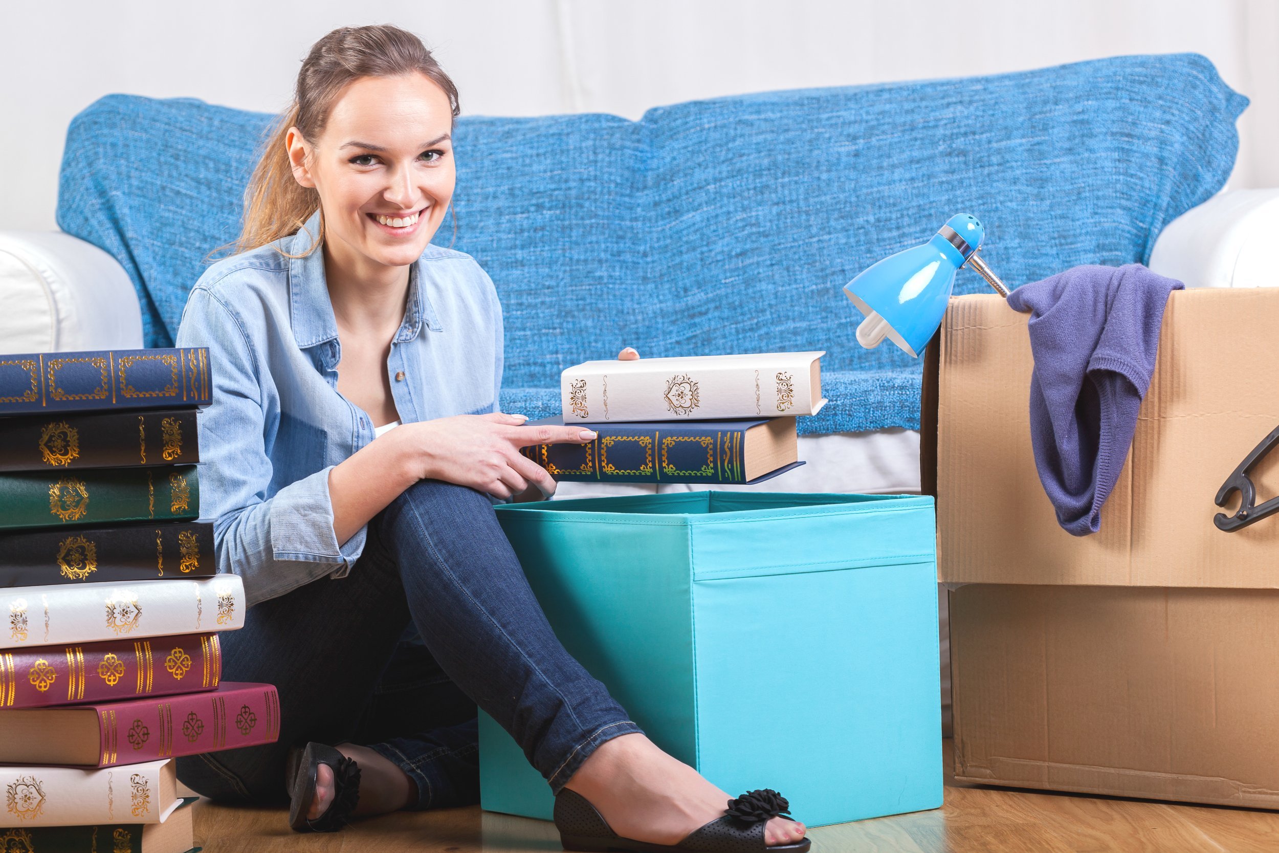 Smiling woman packing books during moving house.