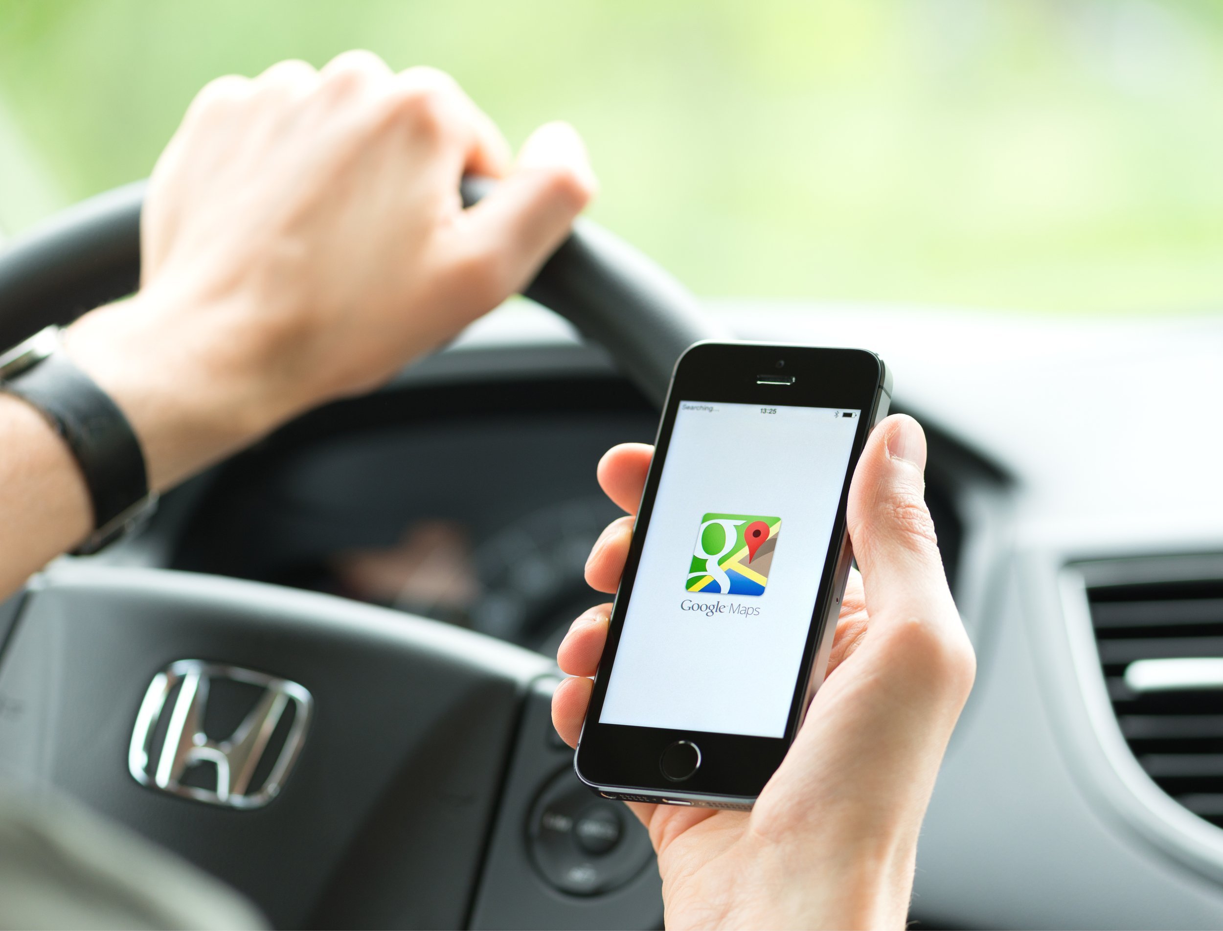 Man in the car using Google Maps application on iPhone.
