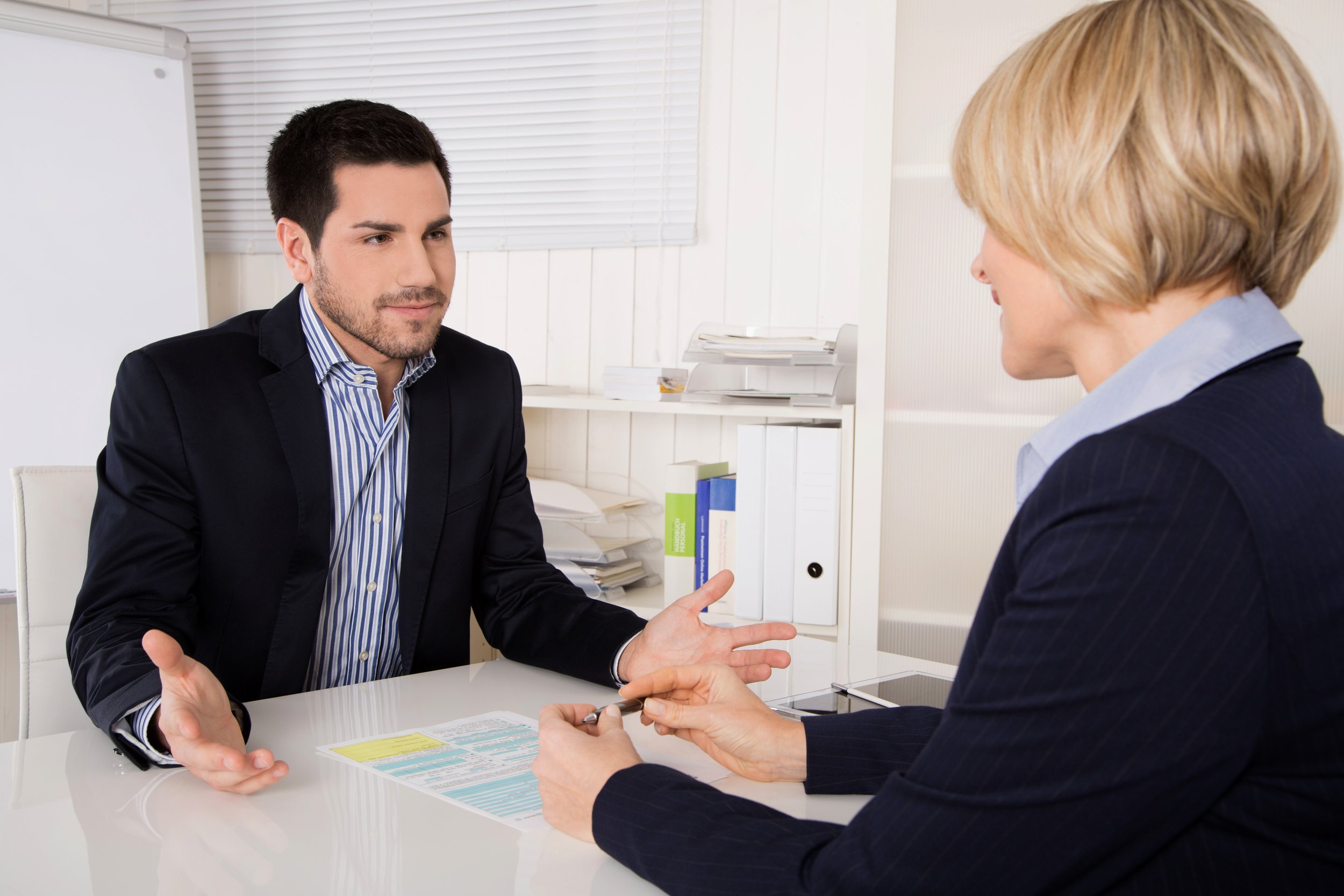 Job interview or meeting situation: business man and woman at desk.