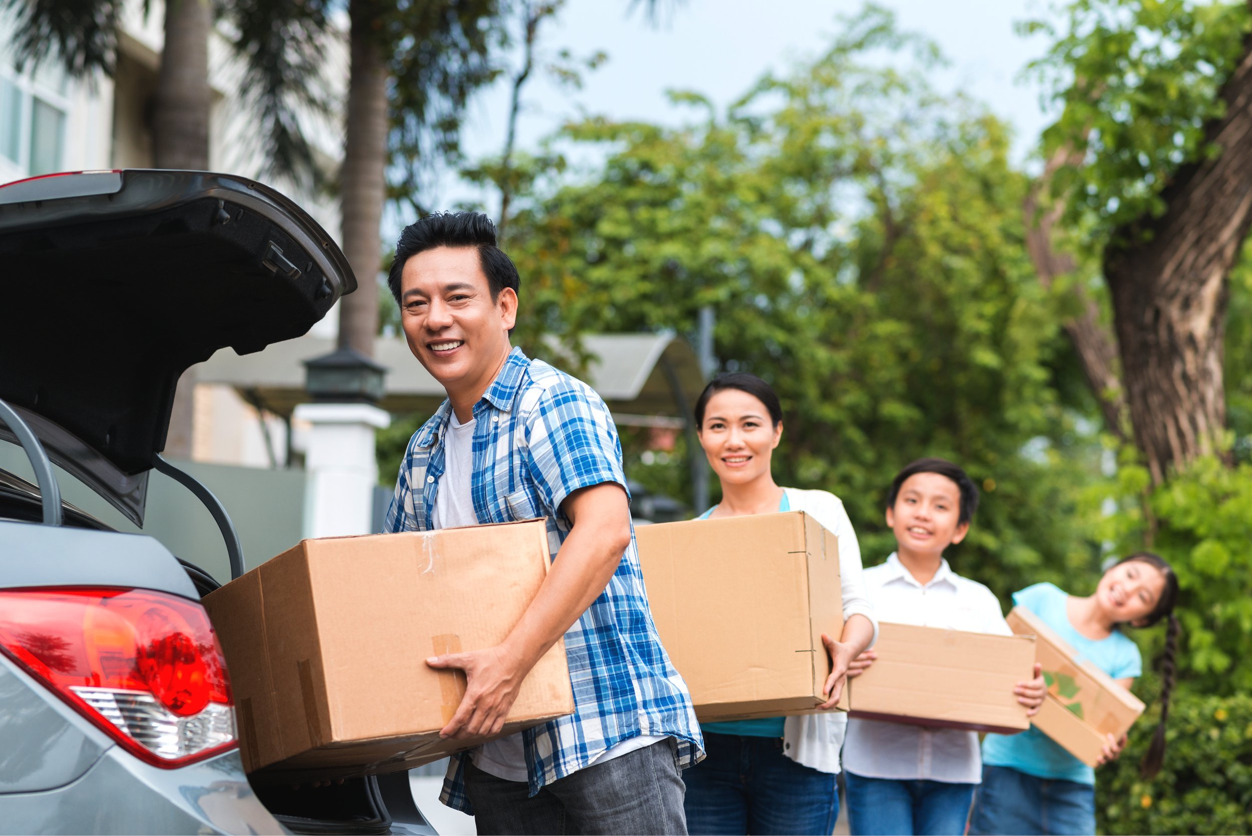 Asian family putting cardboard boxes in the car.