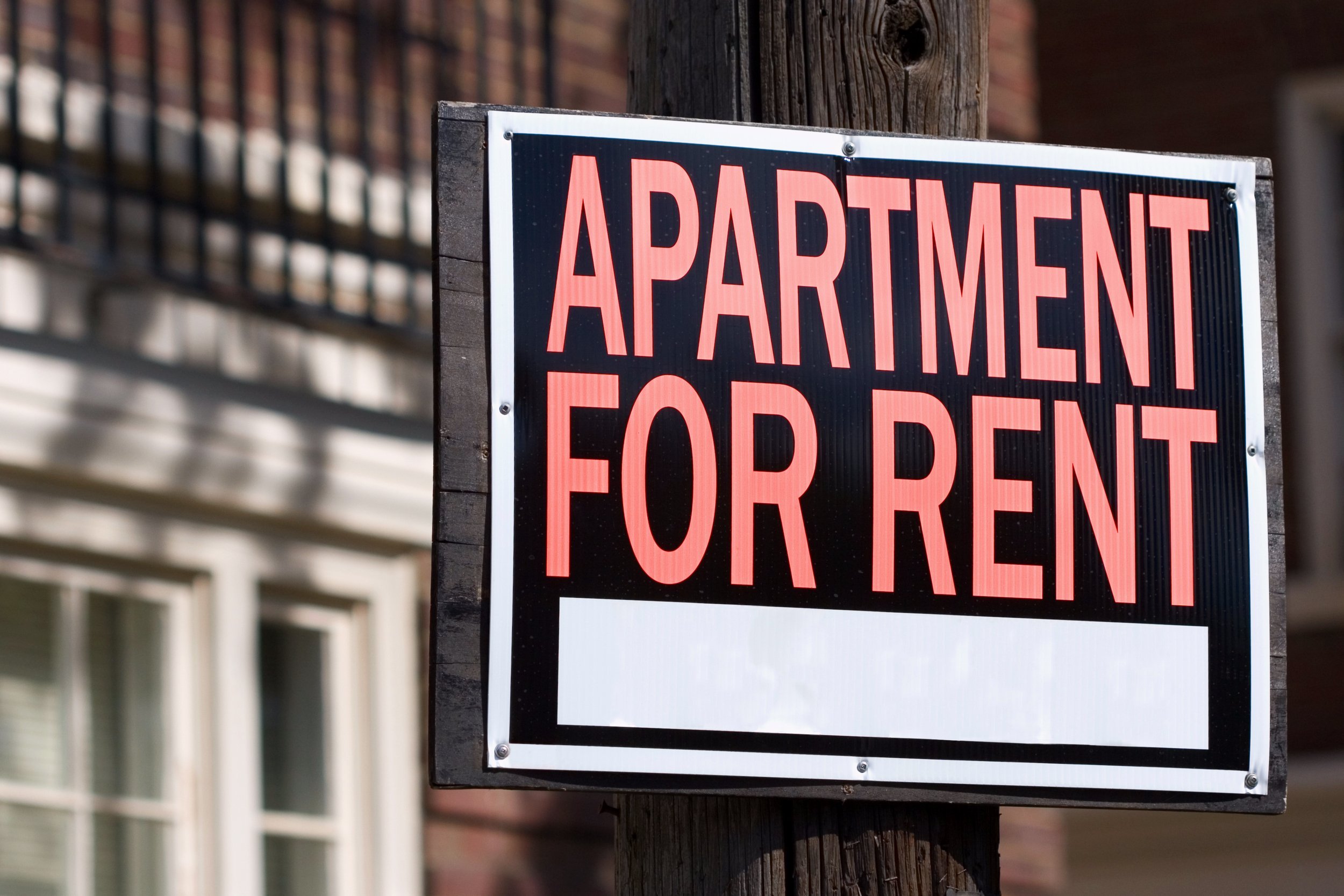 Apartment for rent sign in front of an apartment building.
