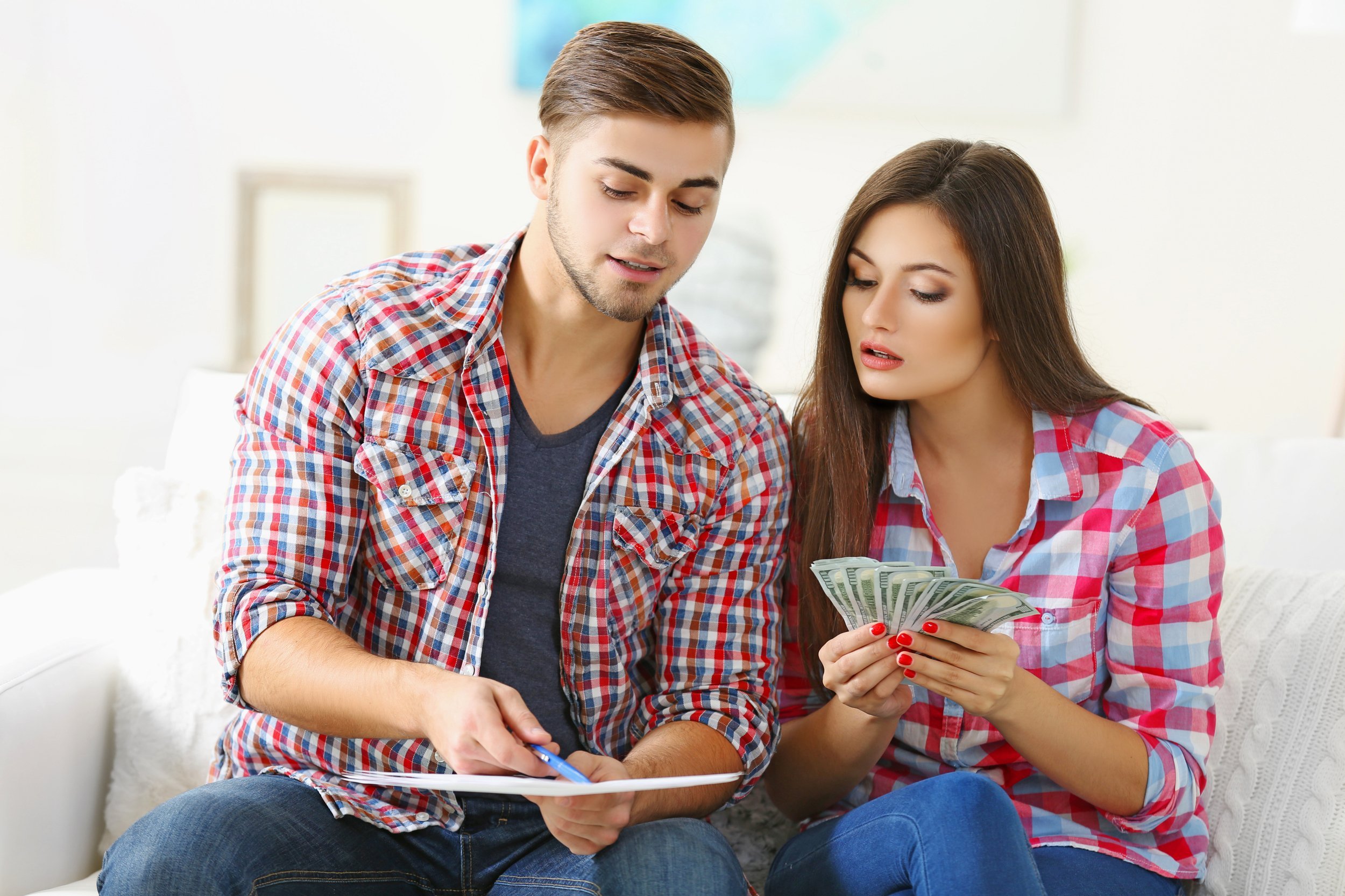young couple sitting and calculating bills at home
