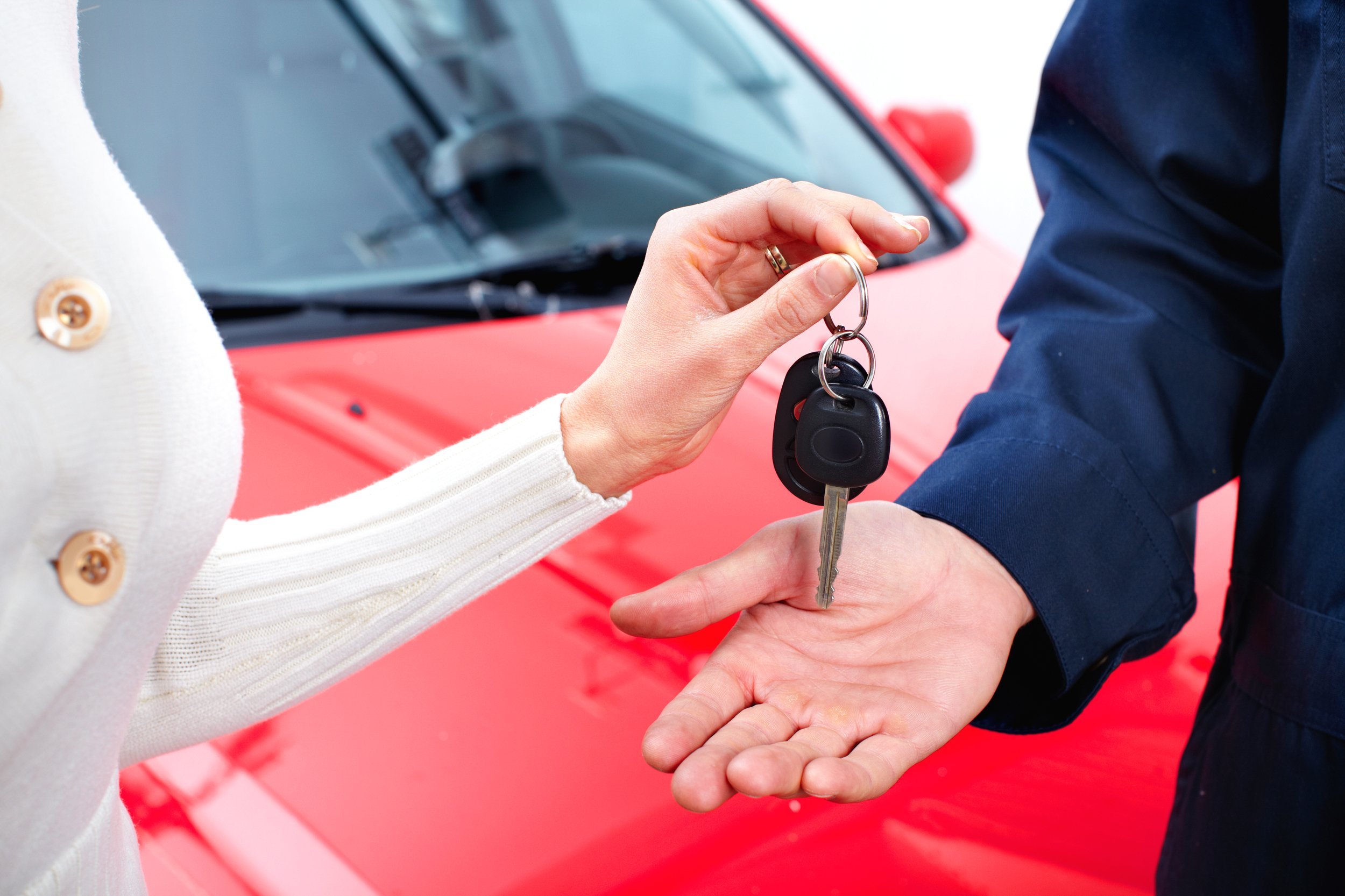 Man handing woman automobile keys for new car.