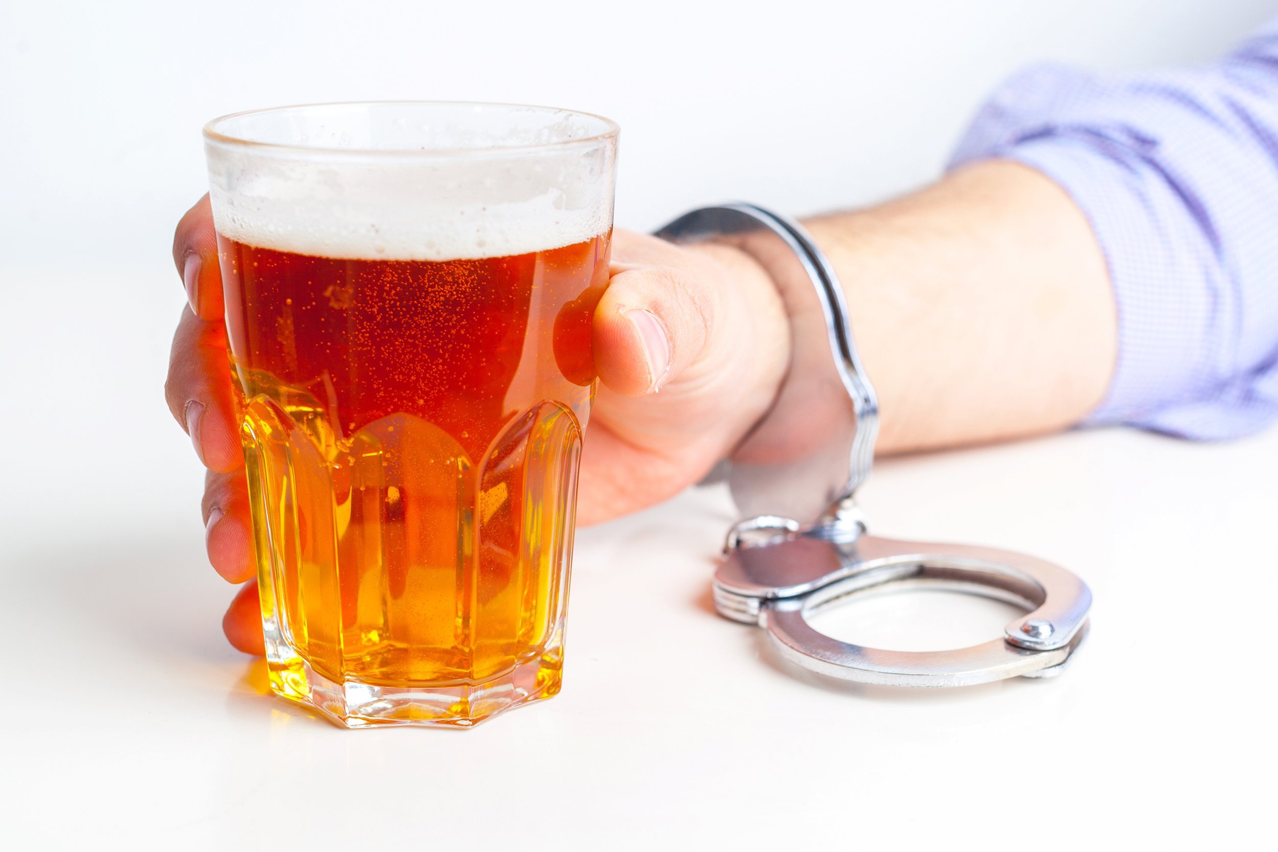 glass of beer with handcuffs as symbol for alcohol abuse