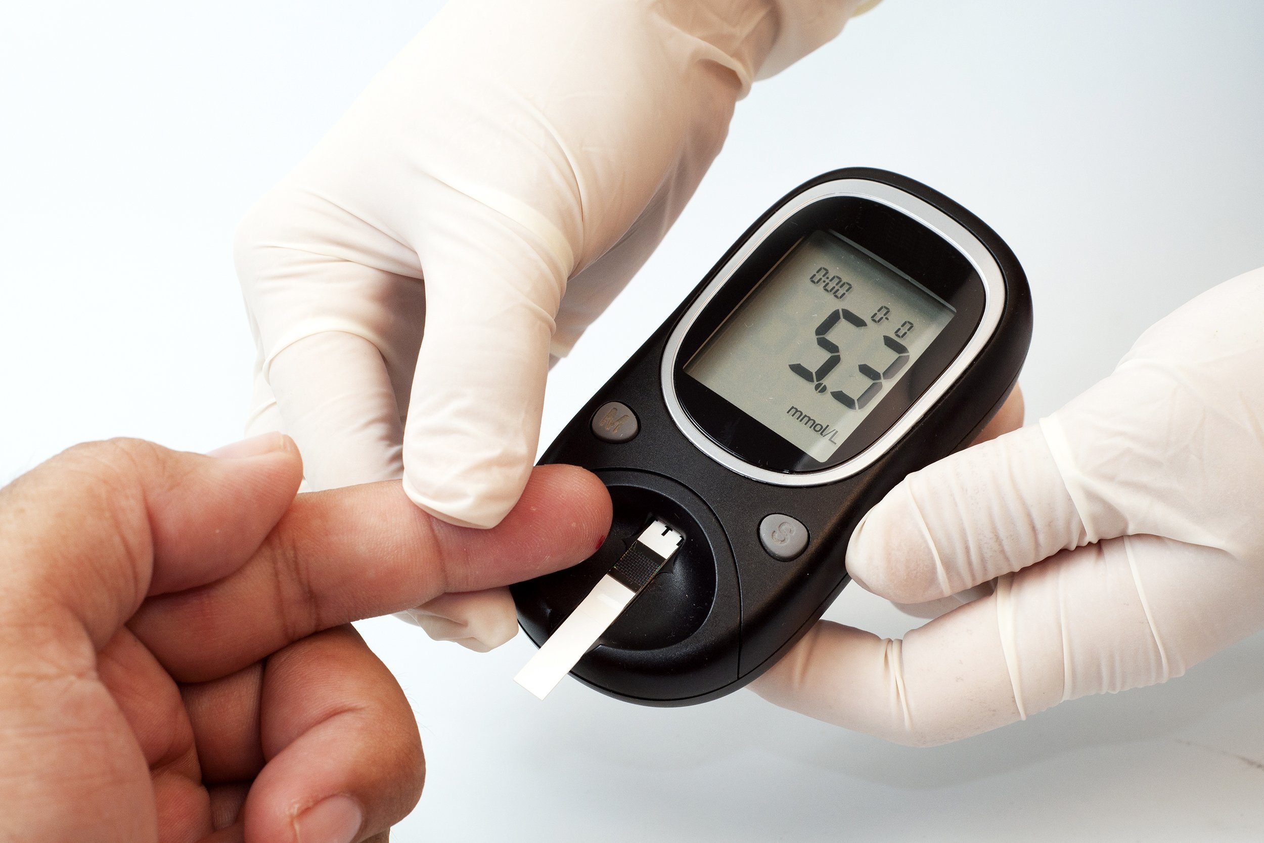 nurse hand measuring glucose level of male patient with a digital glucose meter