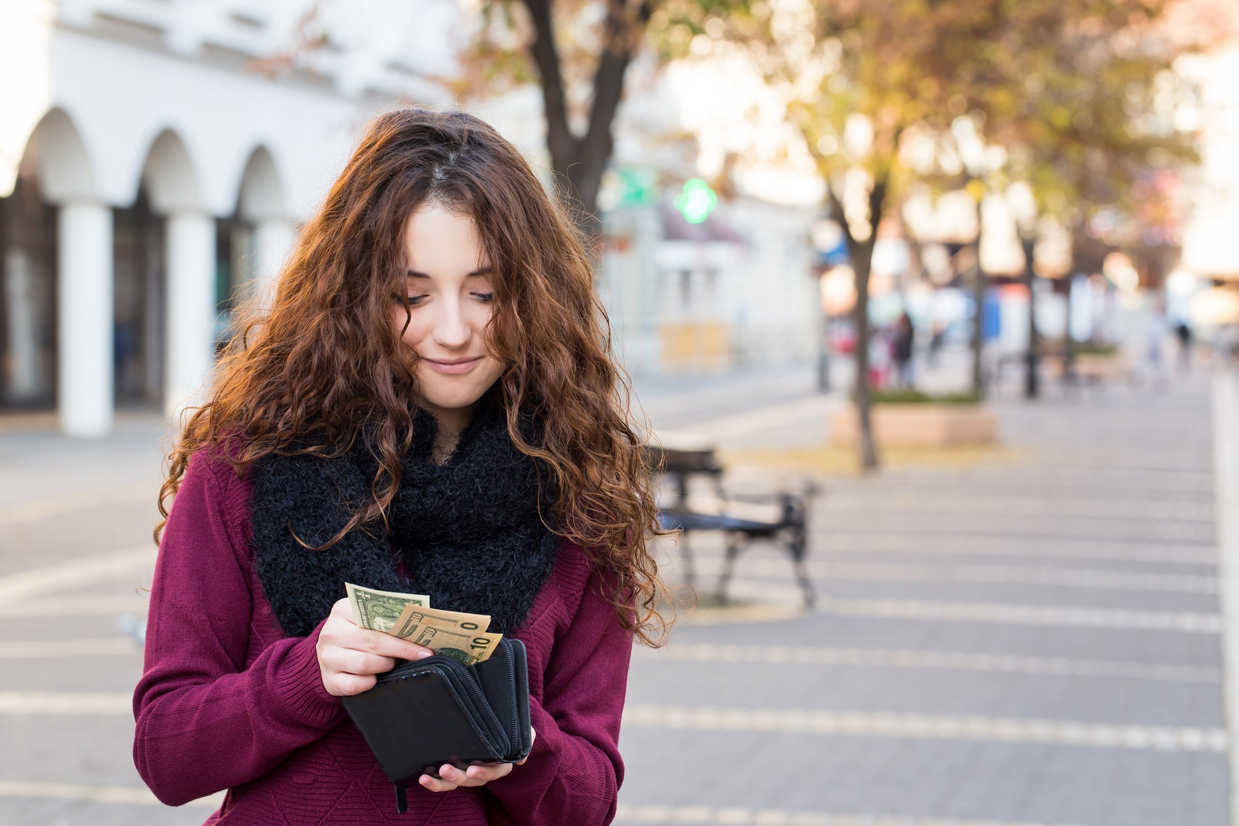 woman taking out money from wallet on street