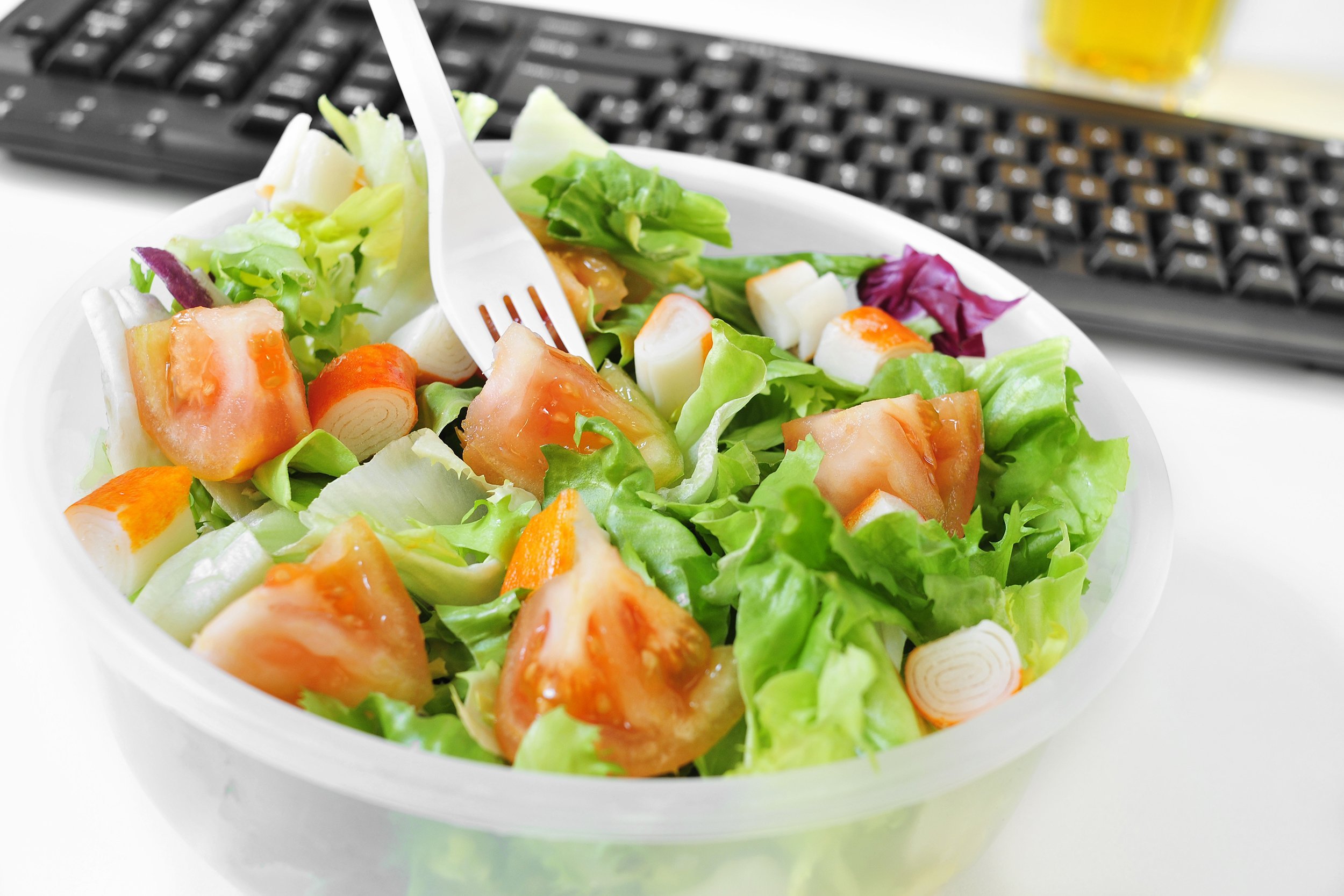 salad in a plastic container on the desk of an office