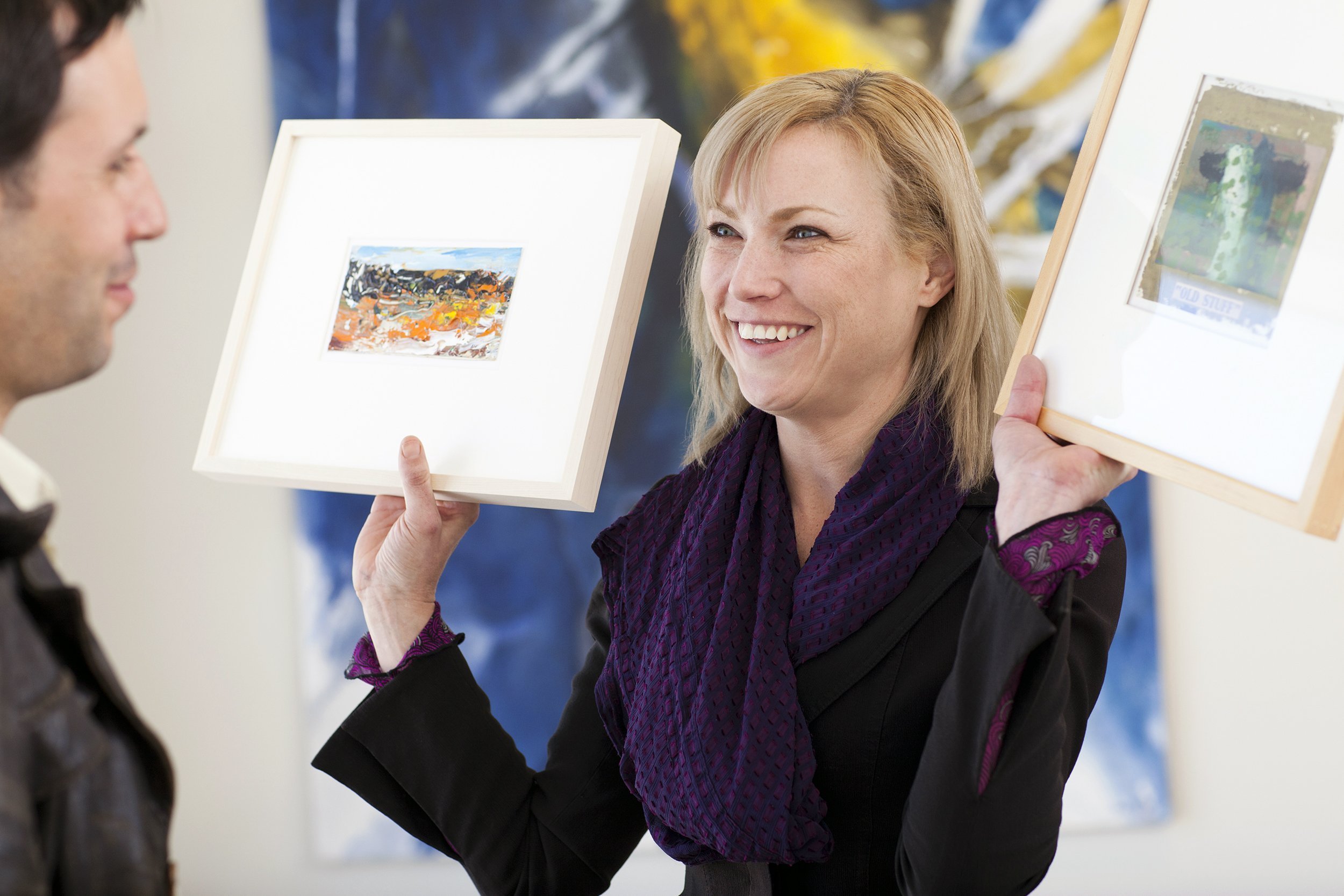 Woman showing two paintings to a customer