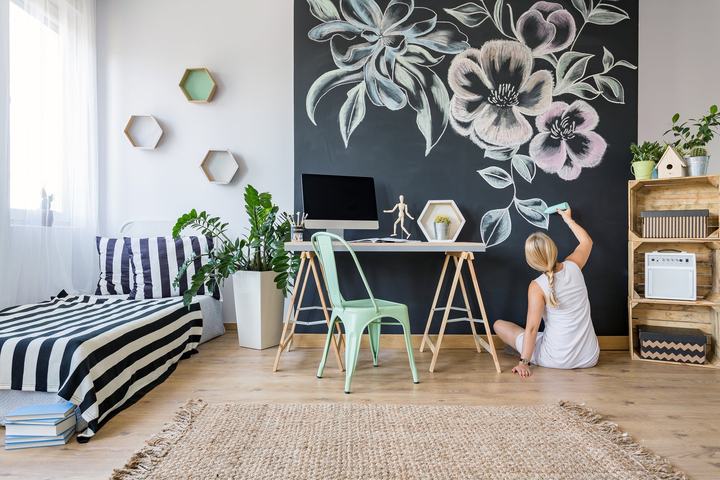Young woman painting mural on a wall in her apartment