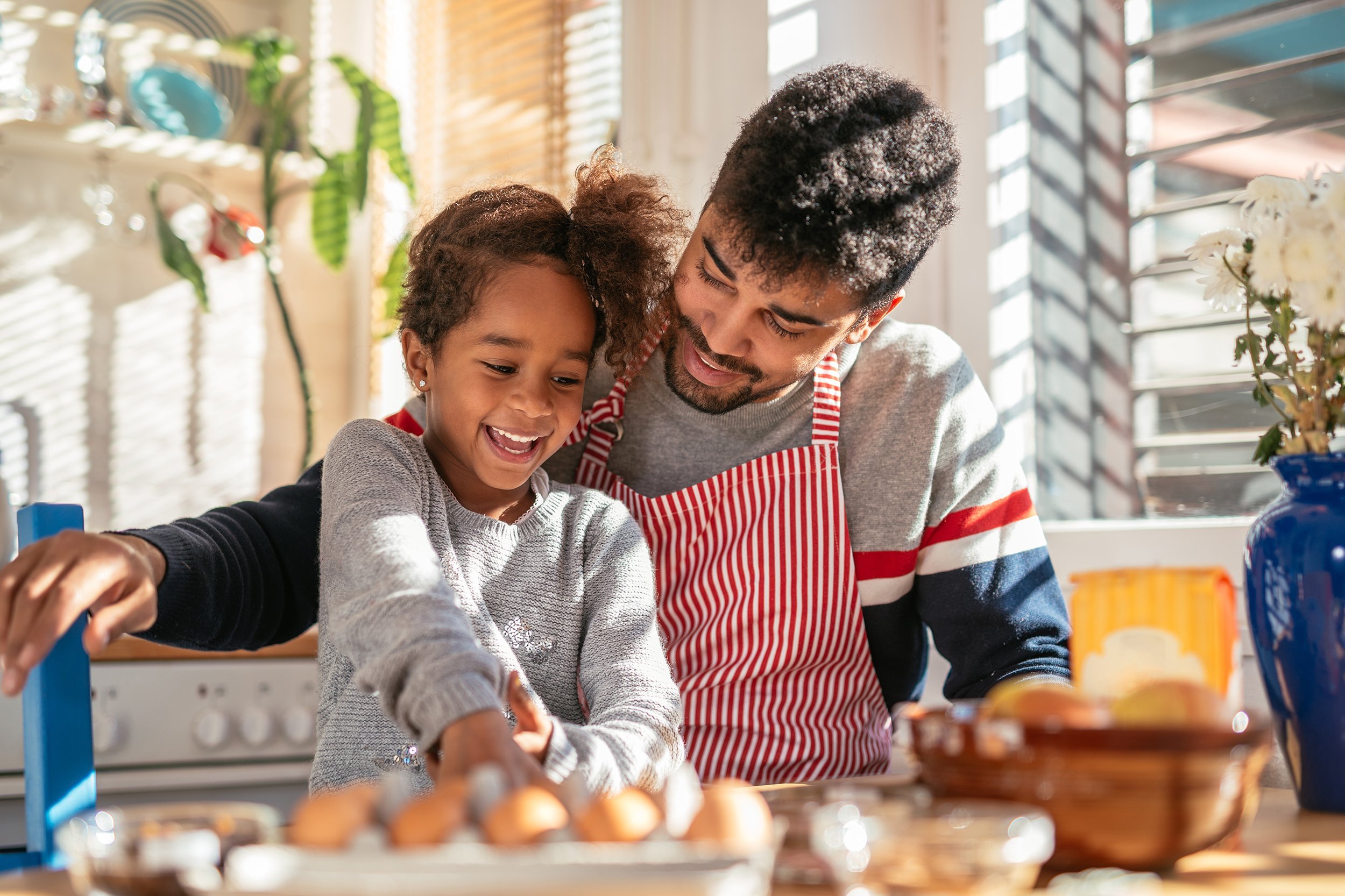 smiling African American father and daughter baking in the kitchen and having fun