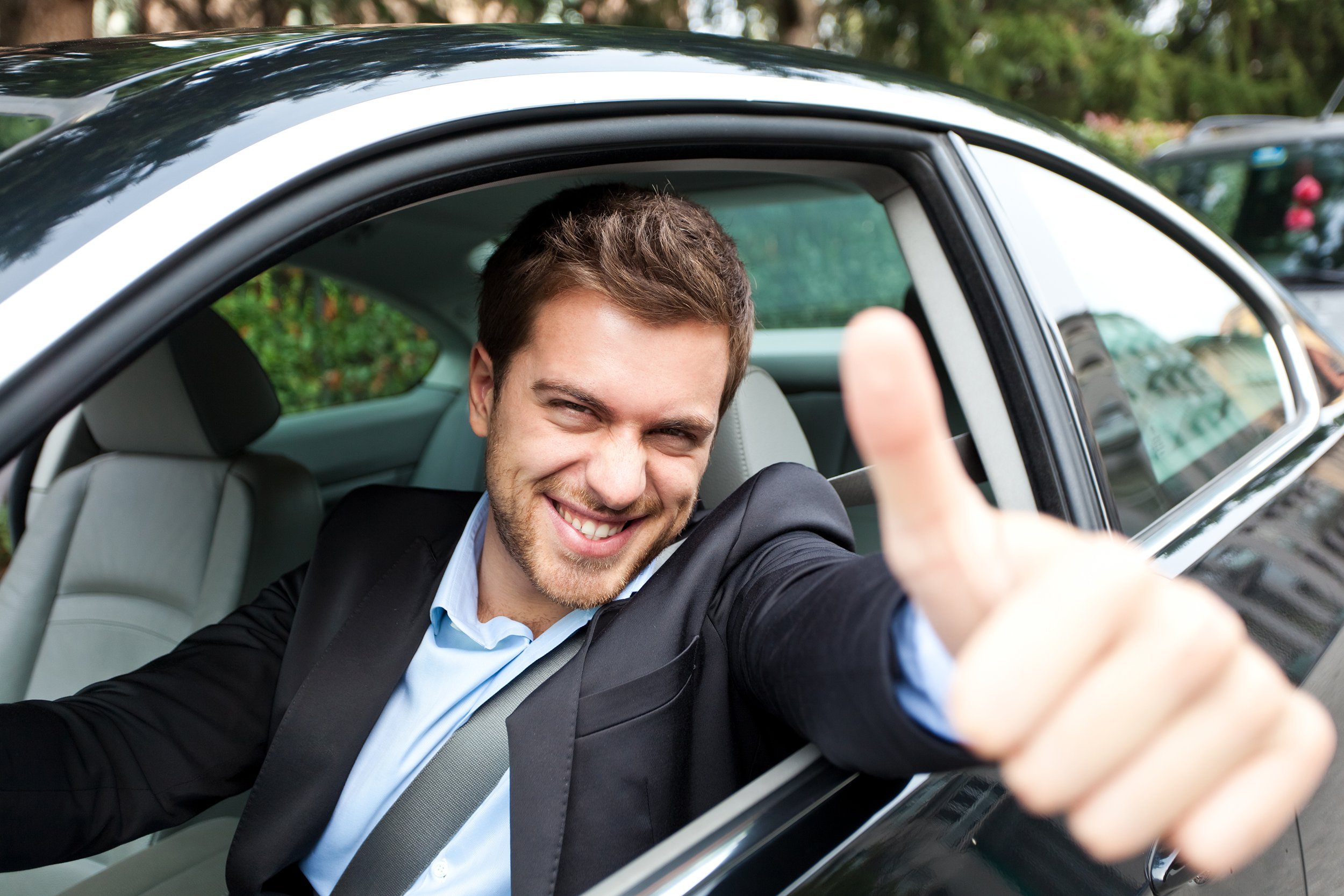 happy man giving thumbs up in his new car