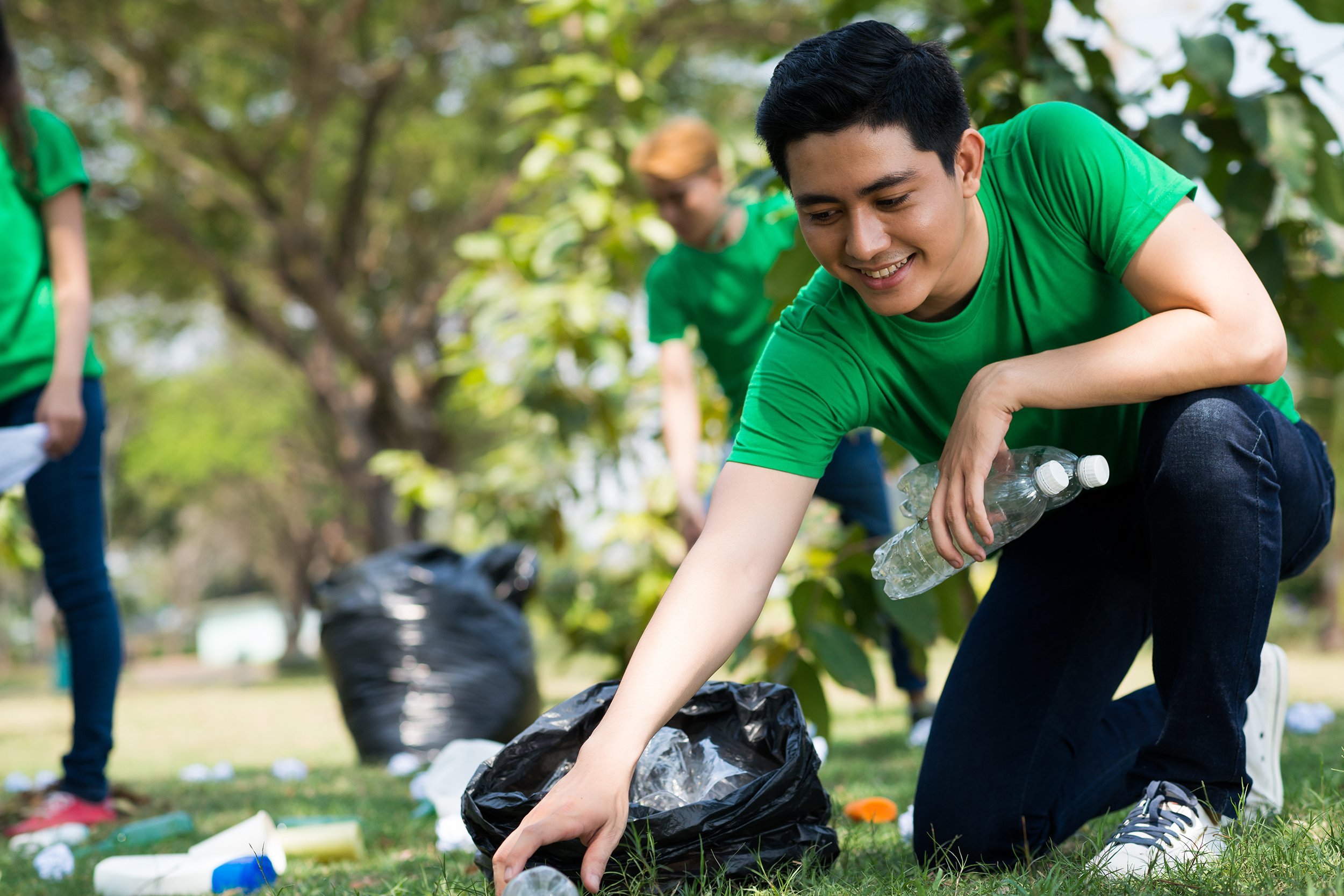 young volunteer picking up plastic bottles in the park