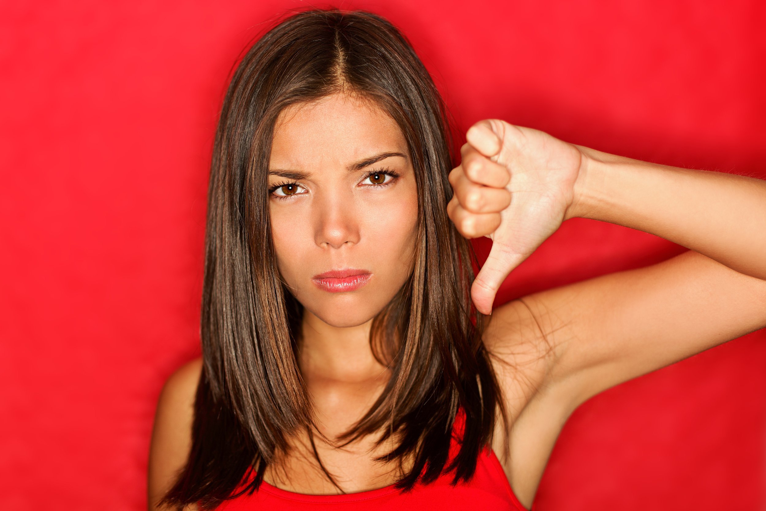 unhappy woman giving thumbs down gesture looking with negative expression and disapproval