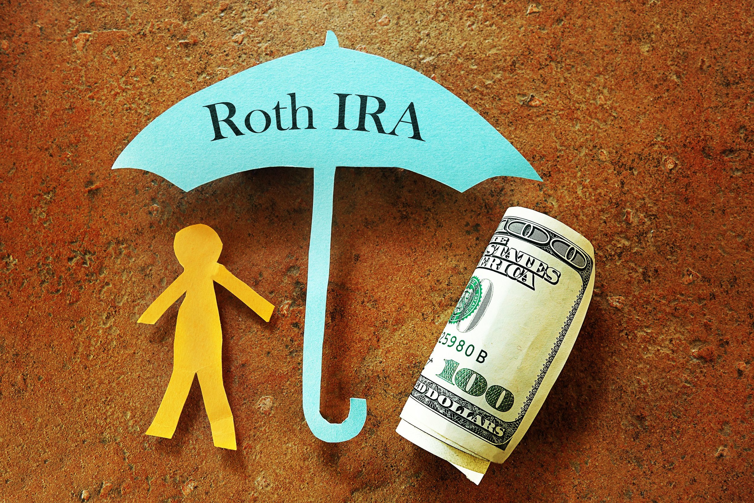 Paper cutout under Roth IRA umbrella with money