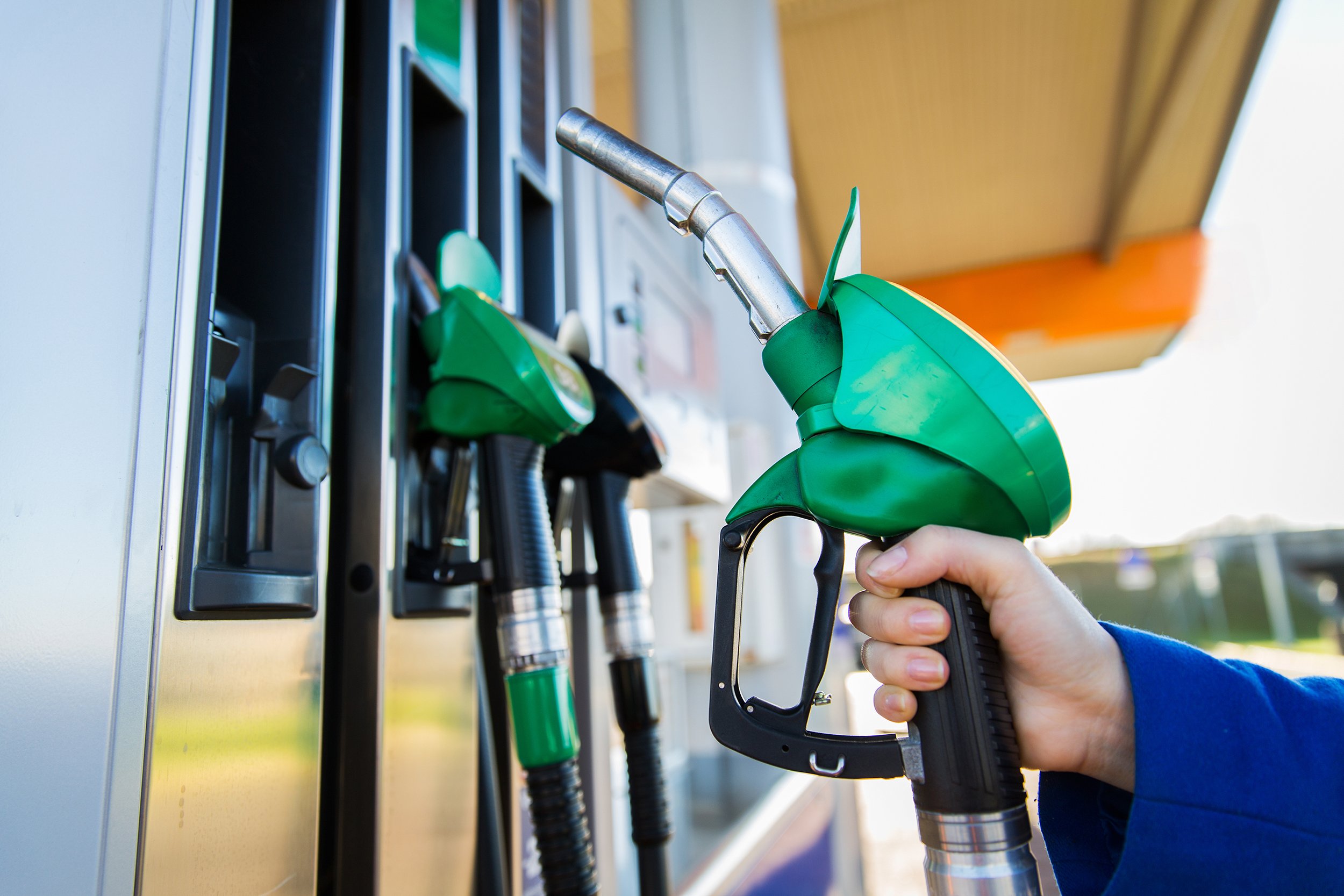 close up of hand holding gasoline hose at gas station
