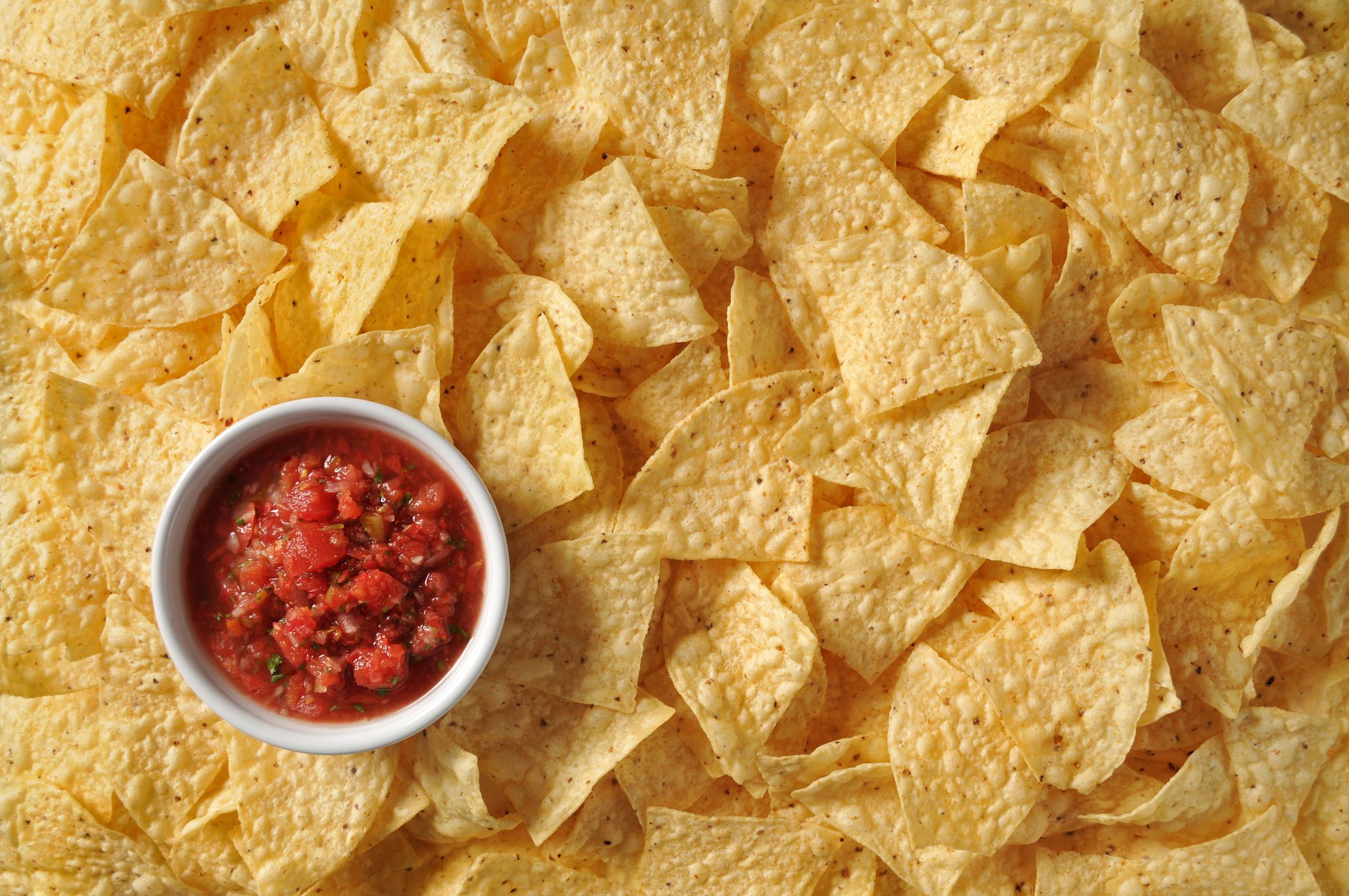Detail studio image of yellow corn tortilla chips and fresh salsa.