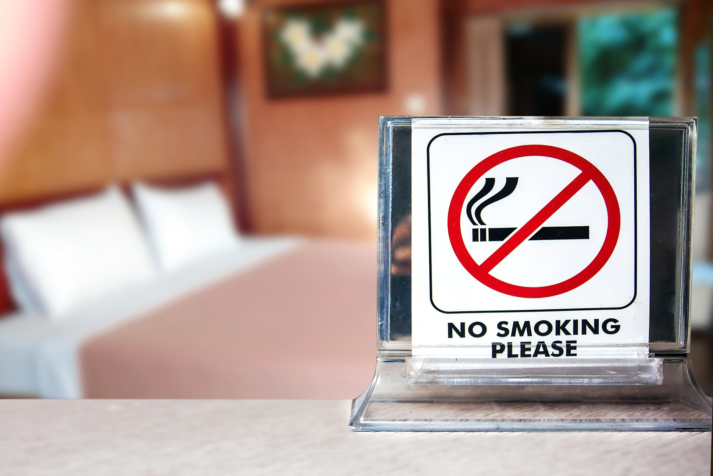 No Smoking sign next to a bed in a hotel room