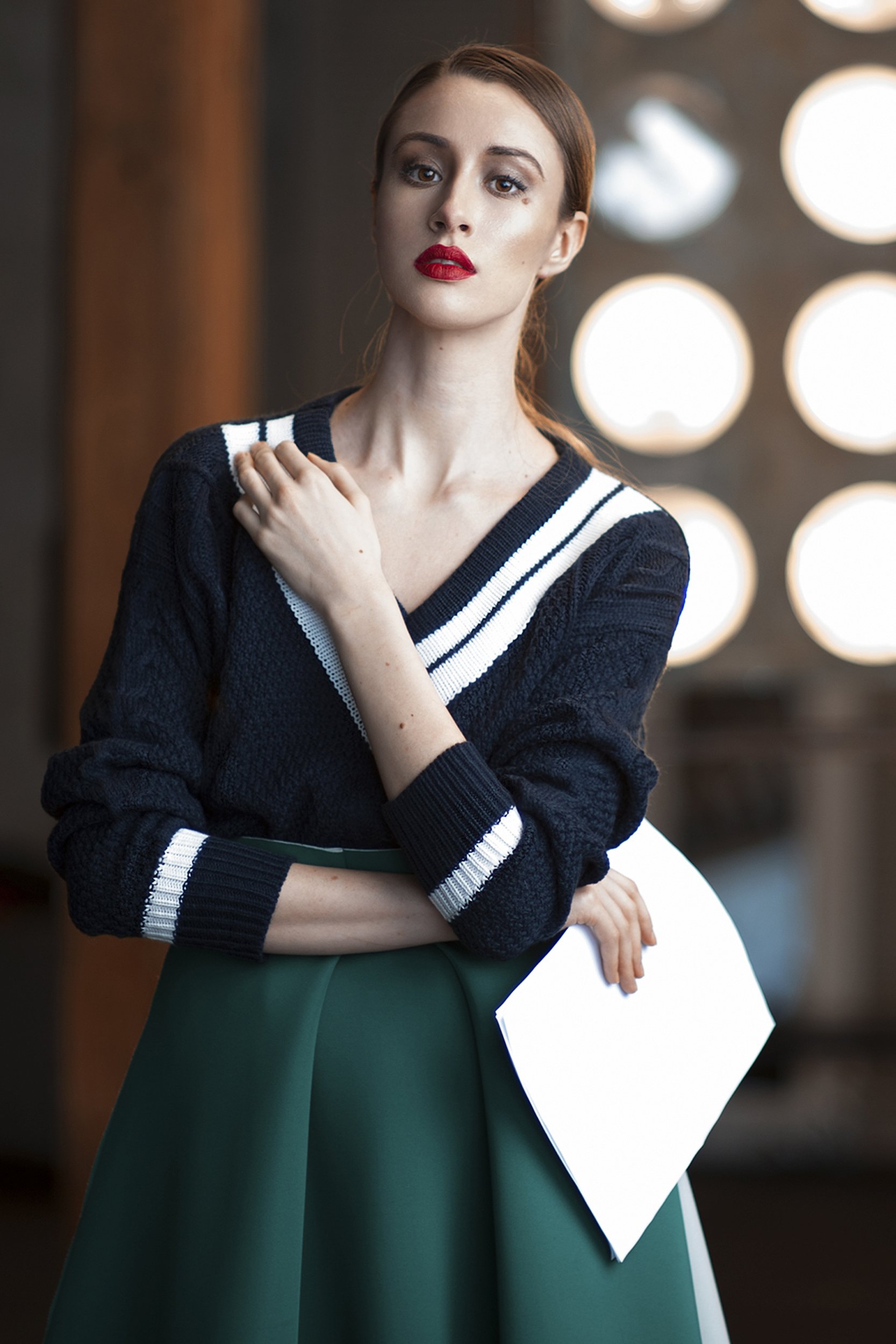 serious young woman standing backstage with her scripts wearing black sweater and green skirt