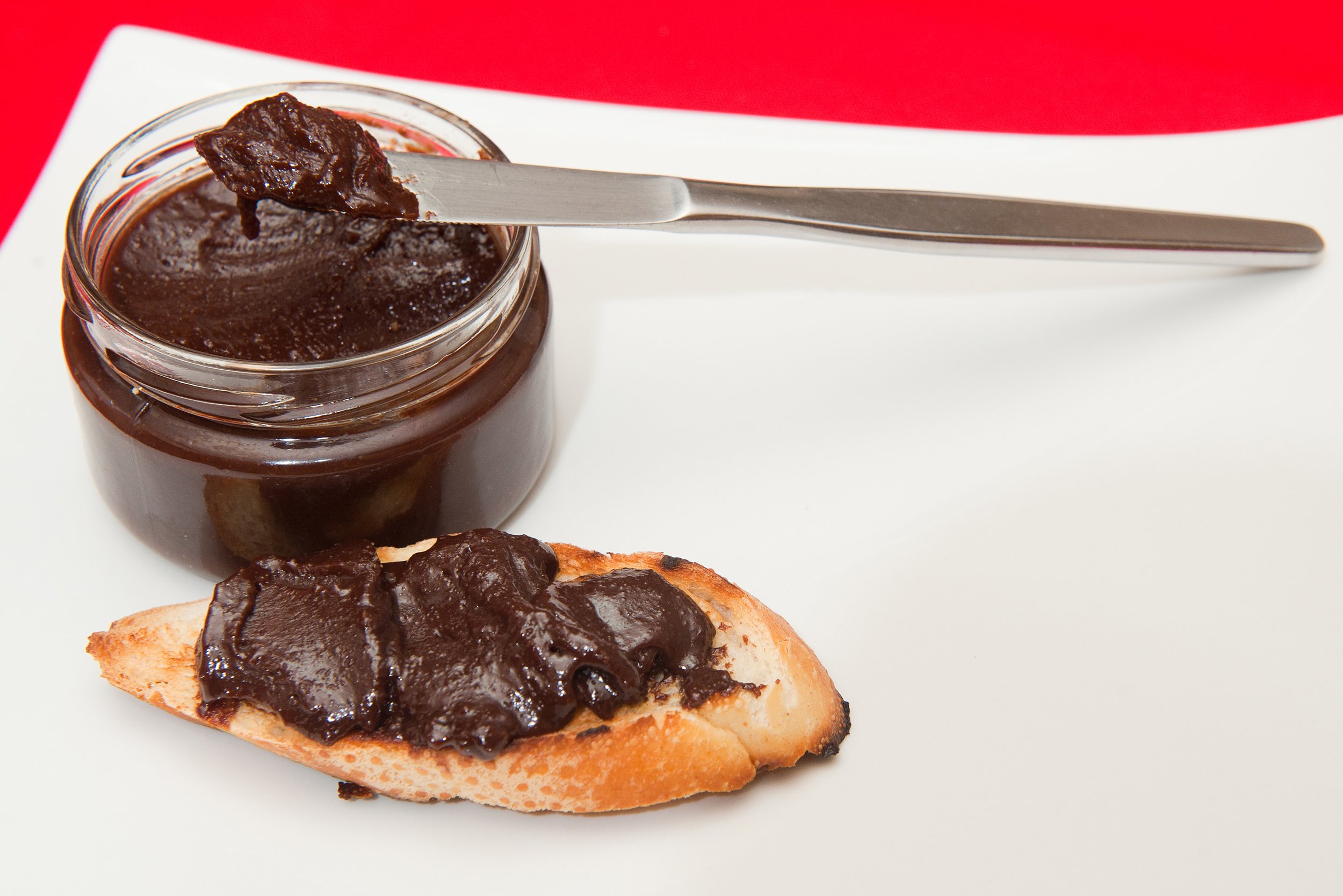Chocolate cookie spread in a jar with a piece of bread