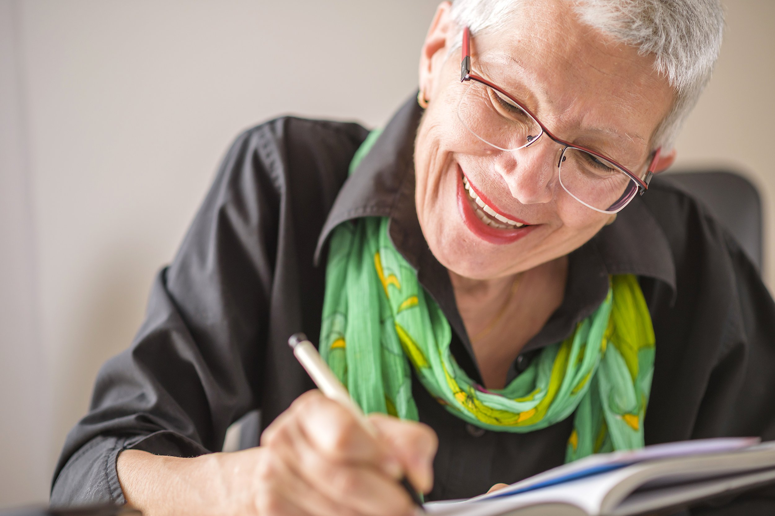 Senior woman smiling and writing in a journal