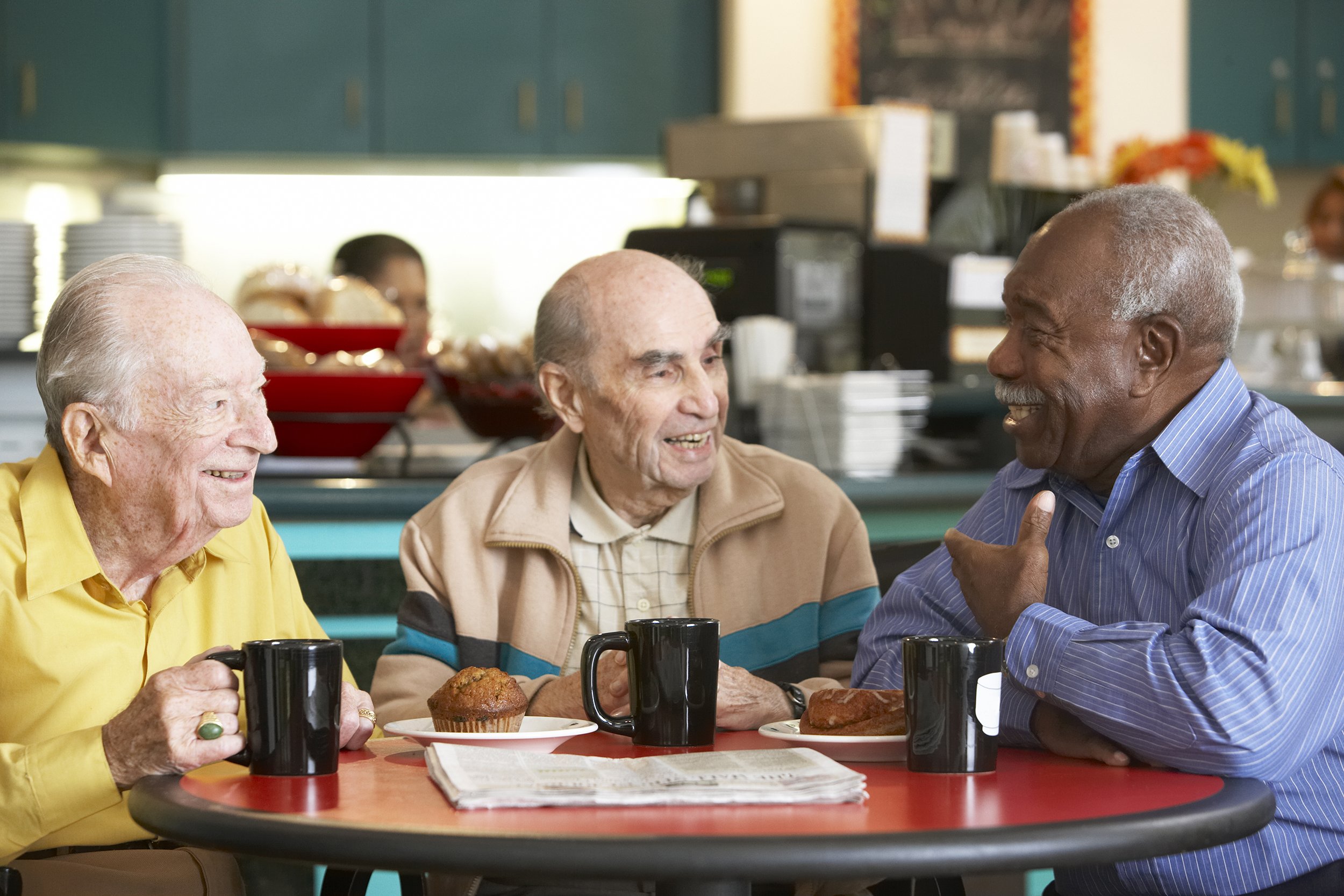 Three senior men drinking coffee or tea together at a cafe