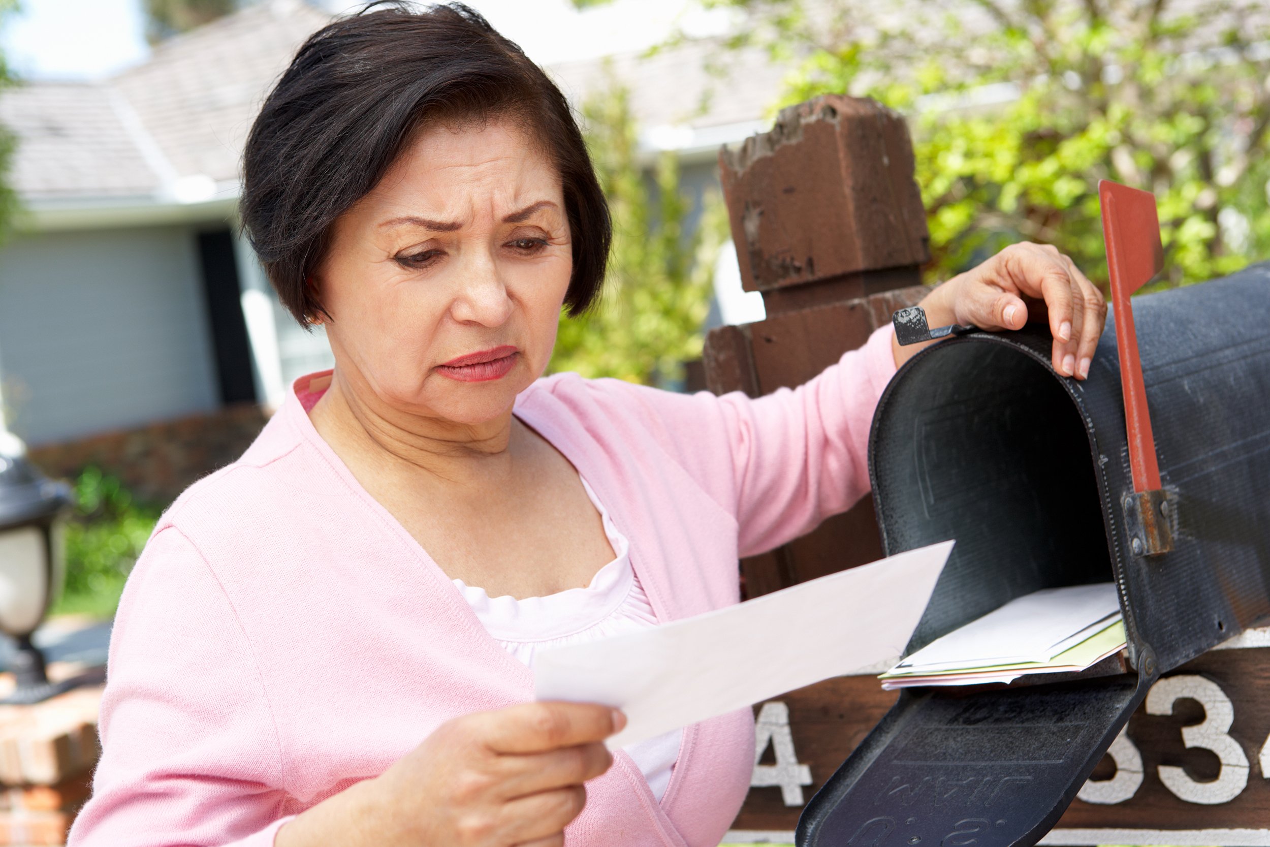 Worried Hispanic woman checking her mail