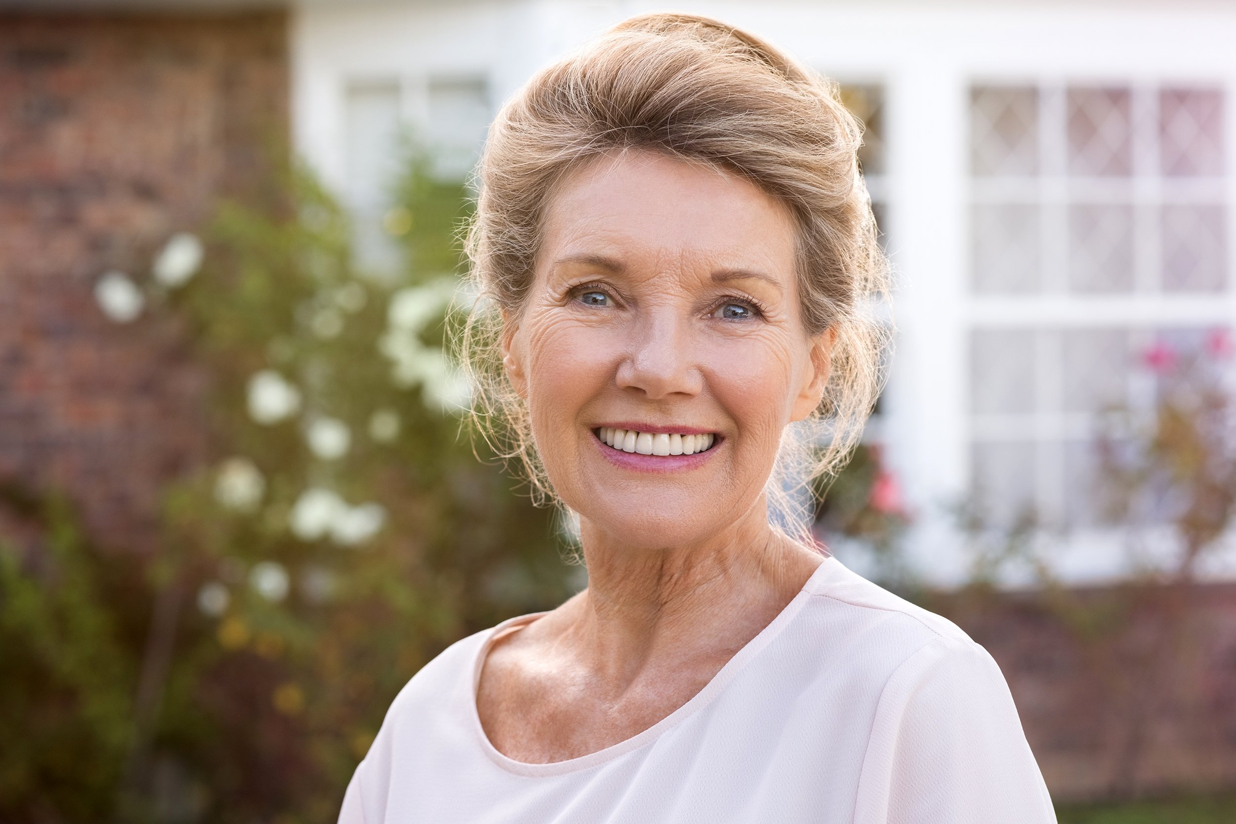 Happy senior woman standing outside her home