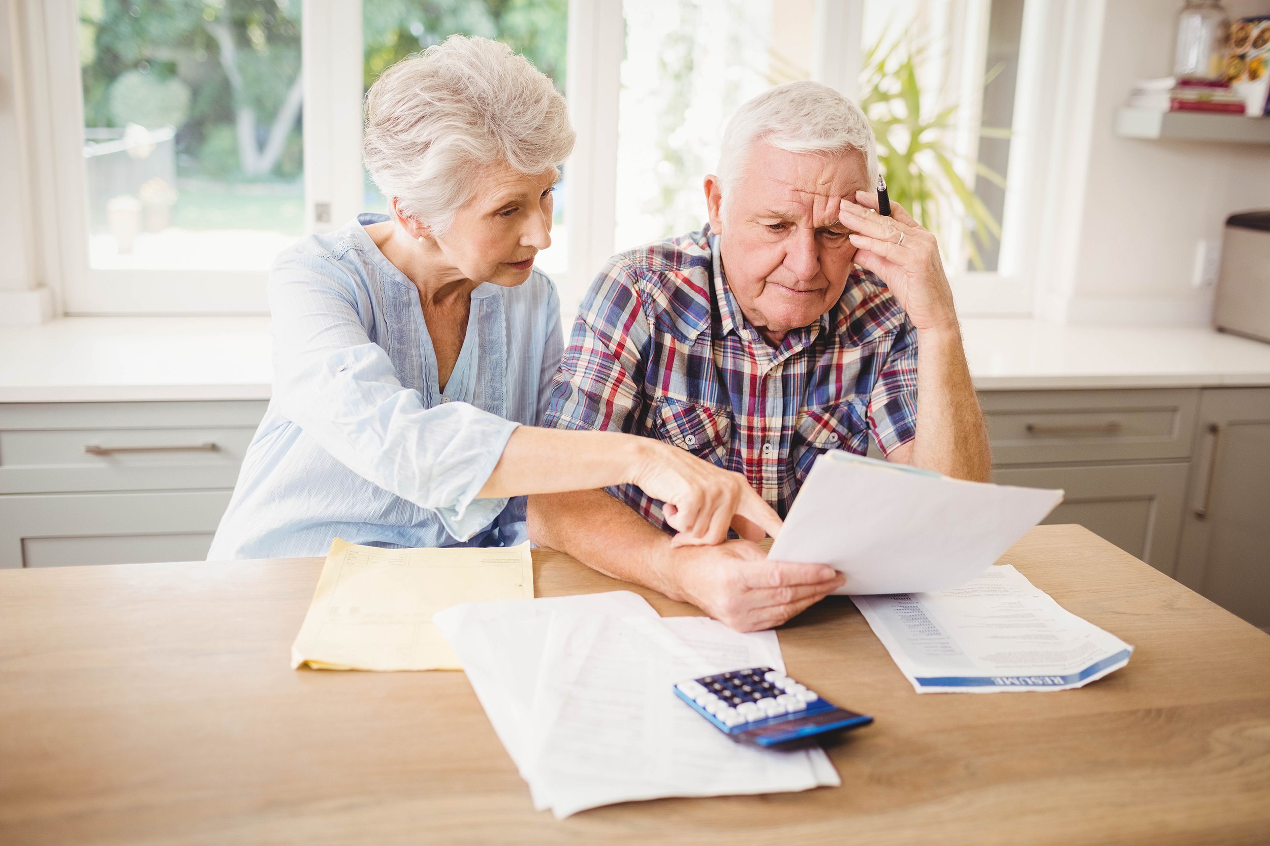 Worried senior couple checking bills