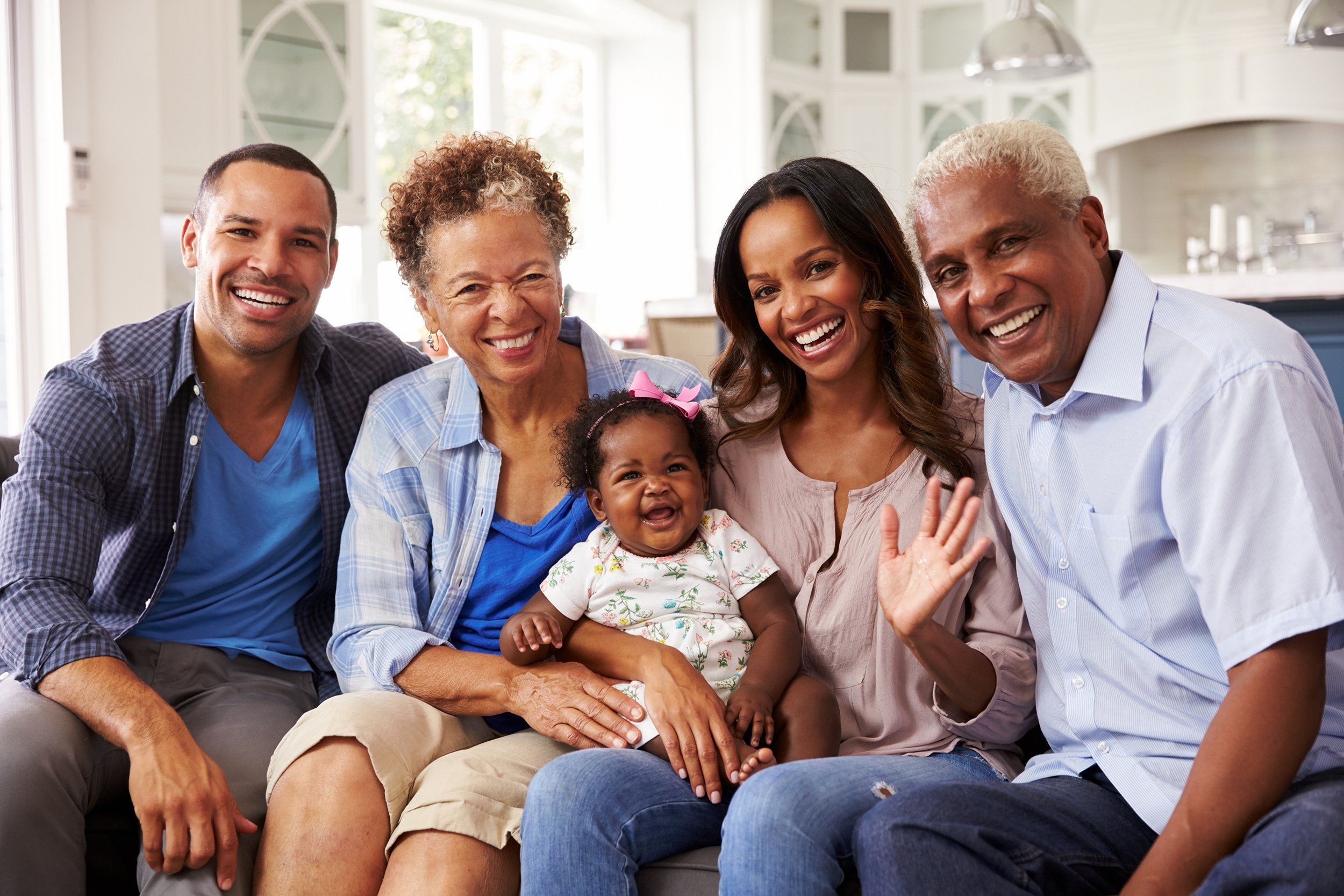 Big family with grandparents and kids sitting at home and smiling at camera