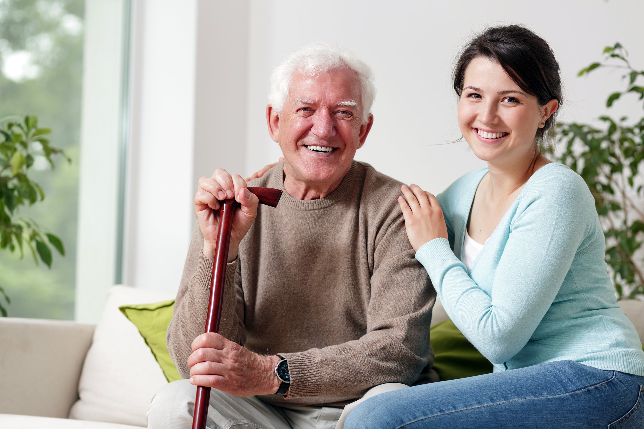 Smiling old man at home with a young daughter or caregiver