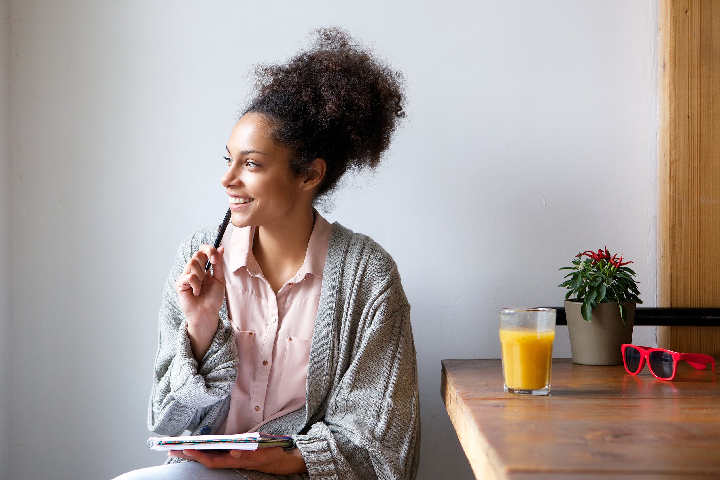 Young woman thoughtfully sitting at home with a pen and paper