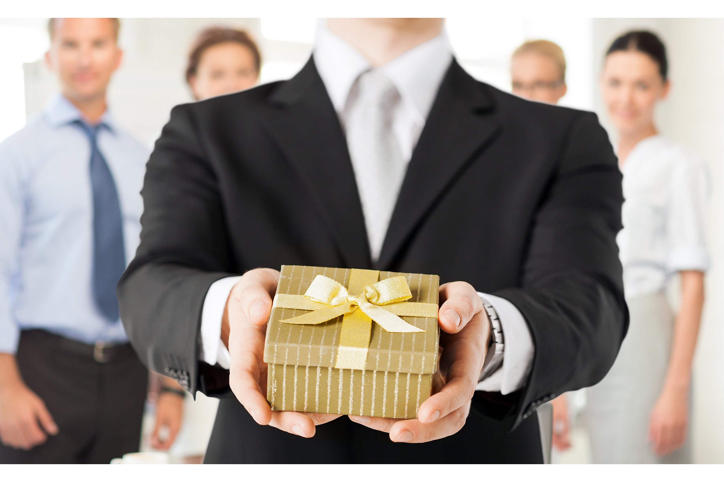 Close-up of businessman holding a present with blurred employees behind