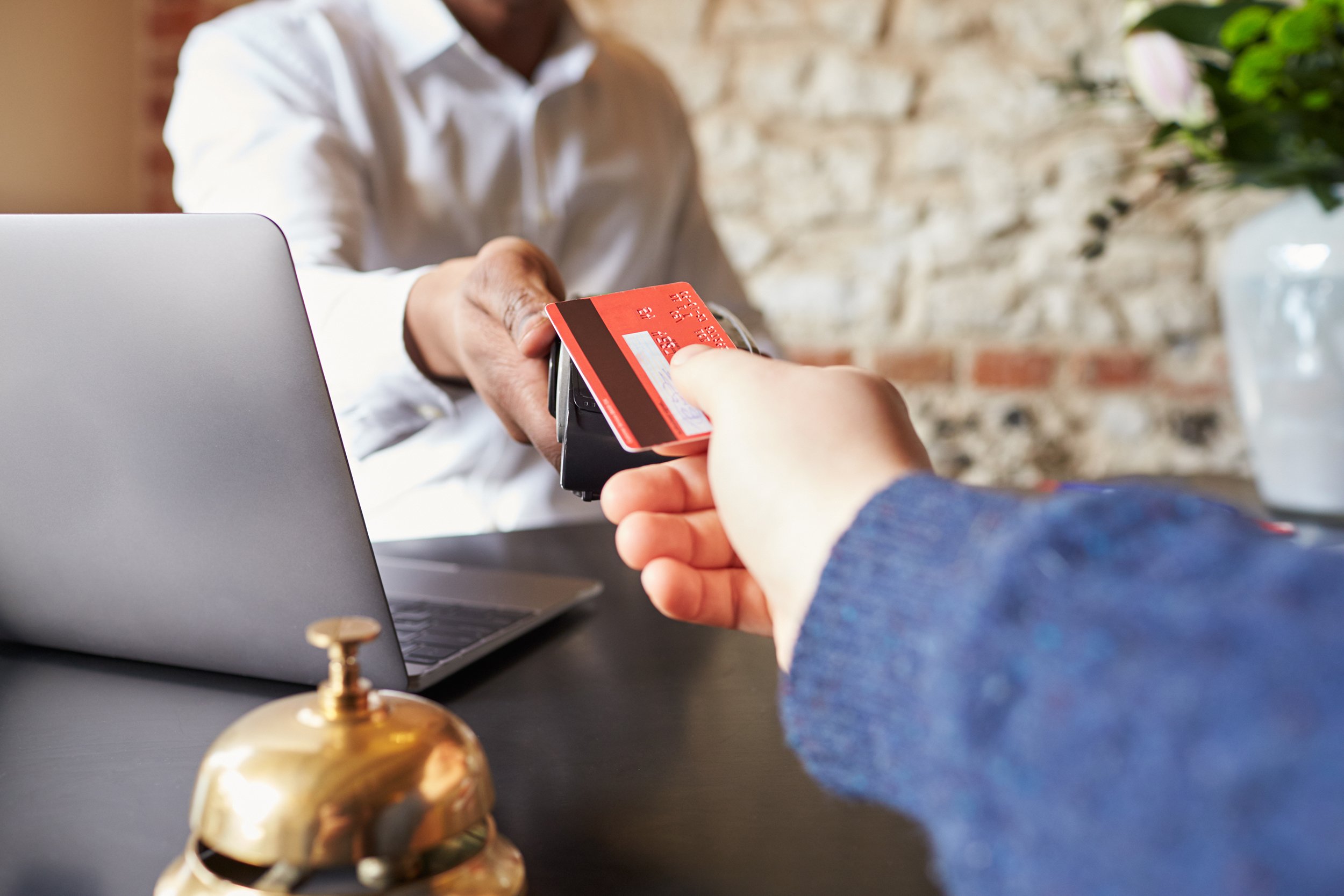 Main handing over credit card to hotel front desk