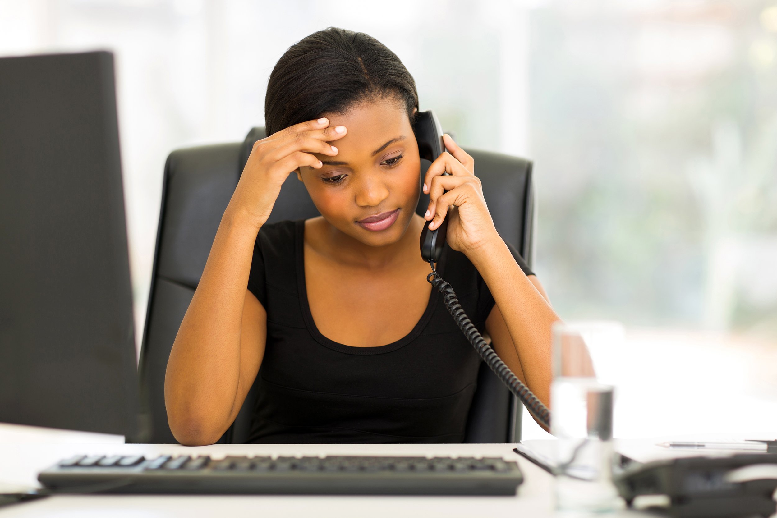 Frustrated looking business woman on the phone at her desk