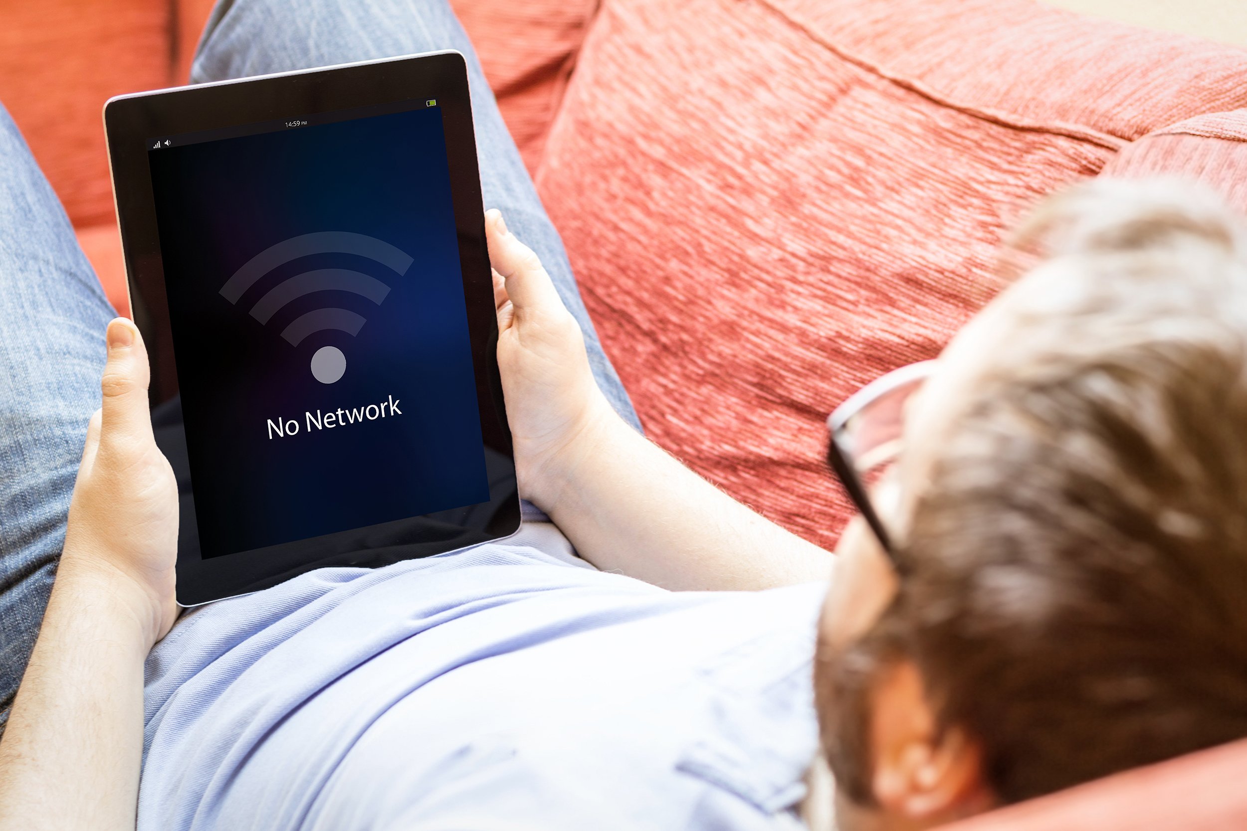 Man lying on couch trying to use his tablet with no wifi