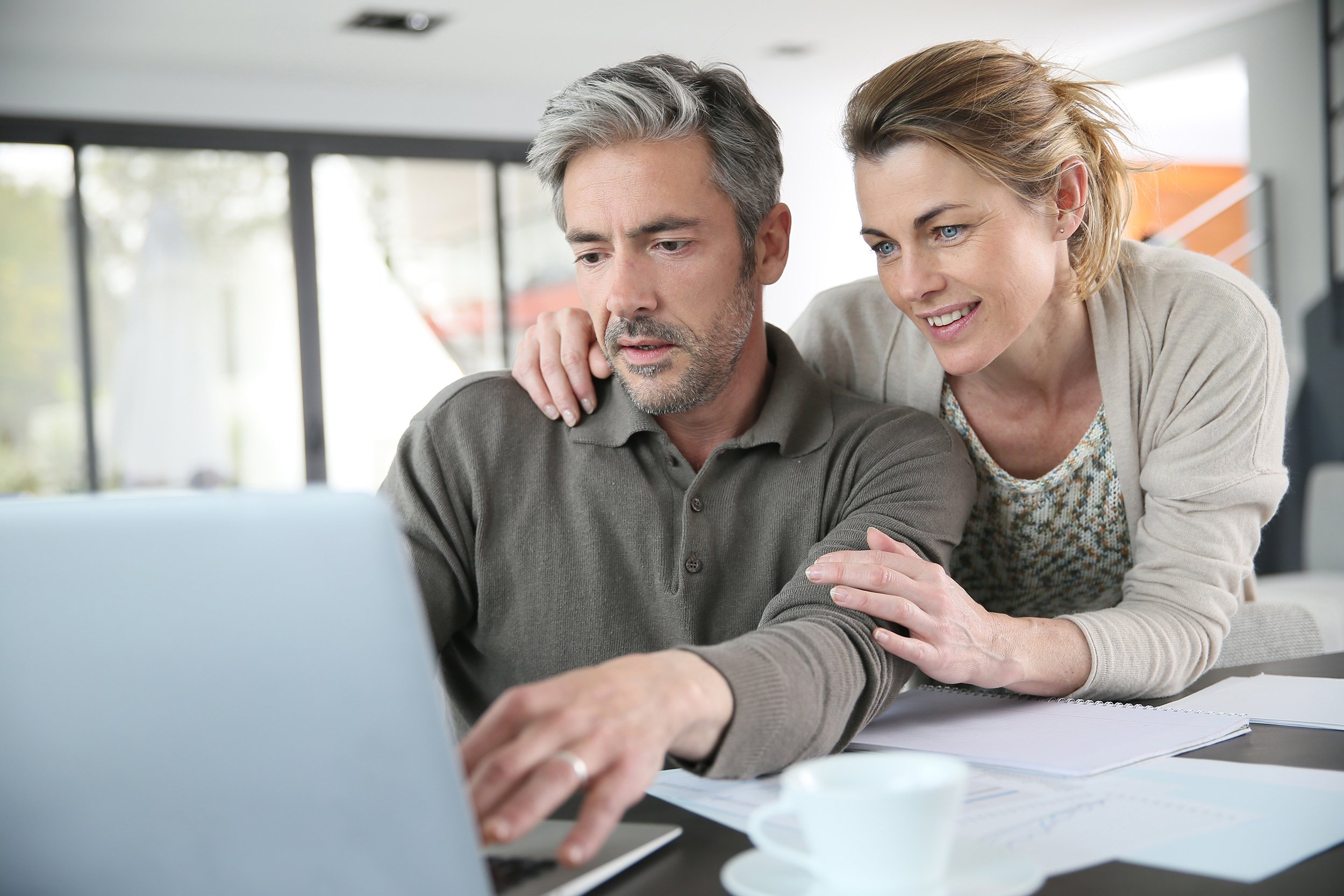 couple calculating financial savings on internet via laptop