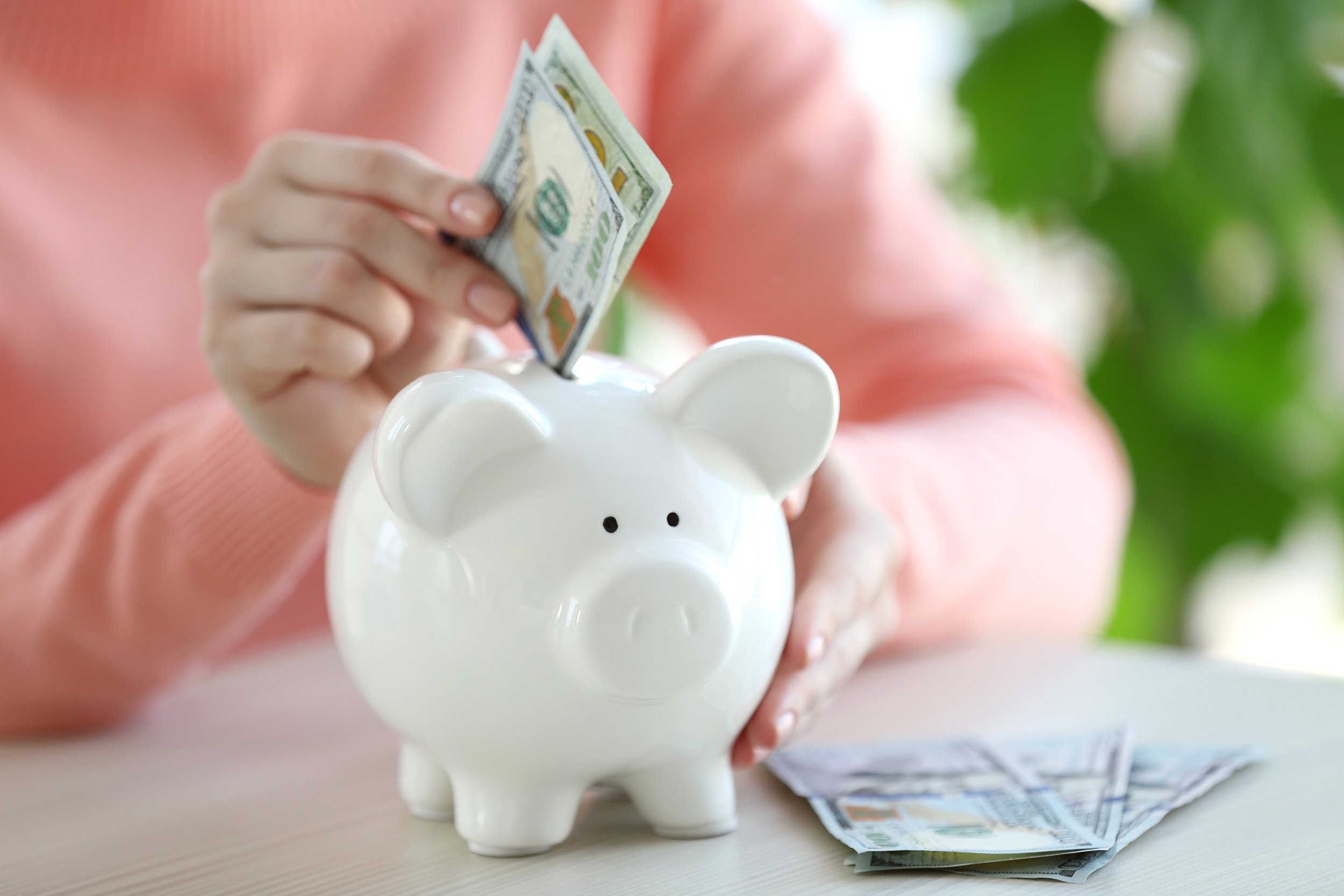 woman putting money in piggy bank