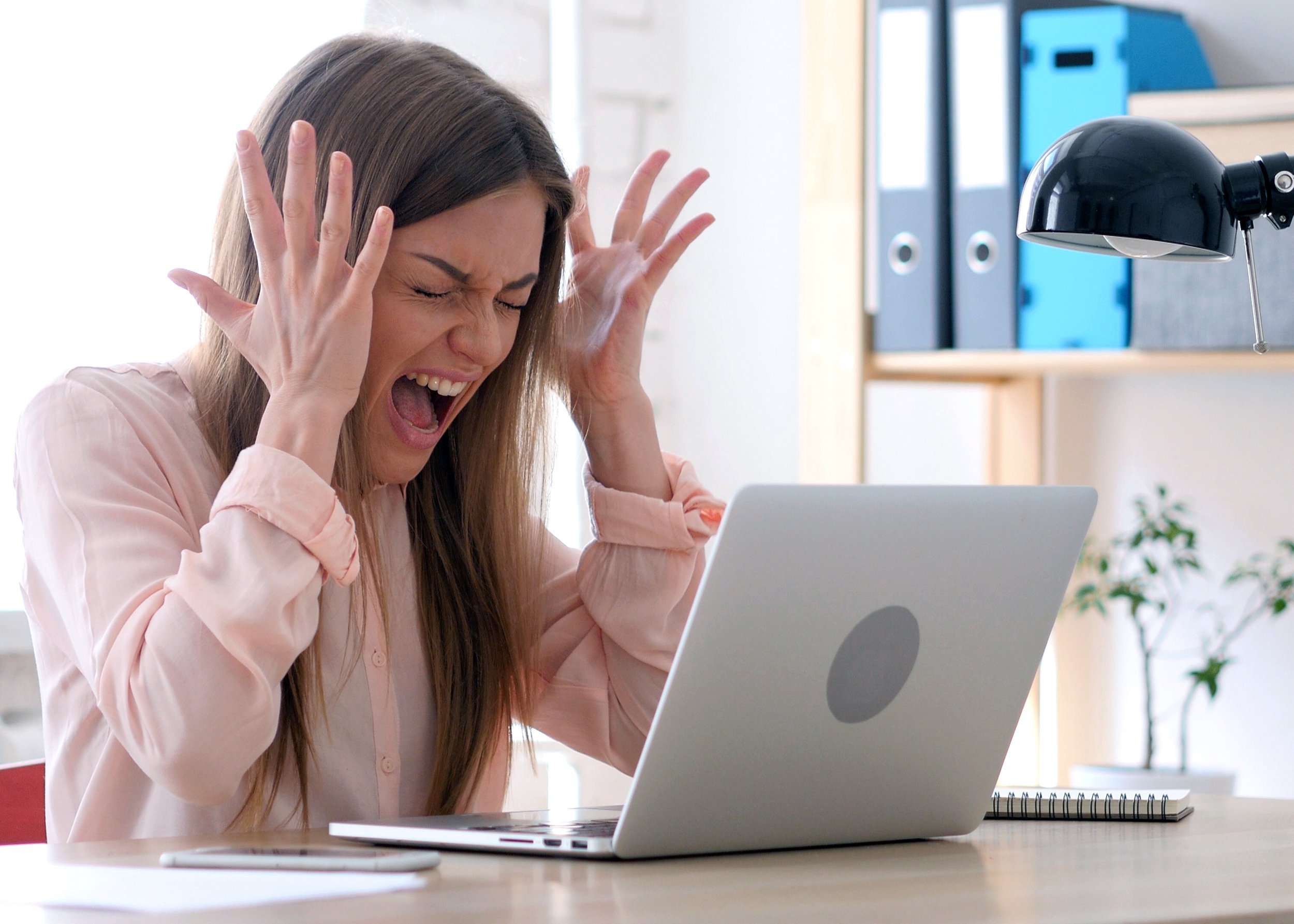 frustrated woman screaming while on the laptop at home