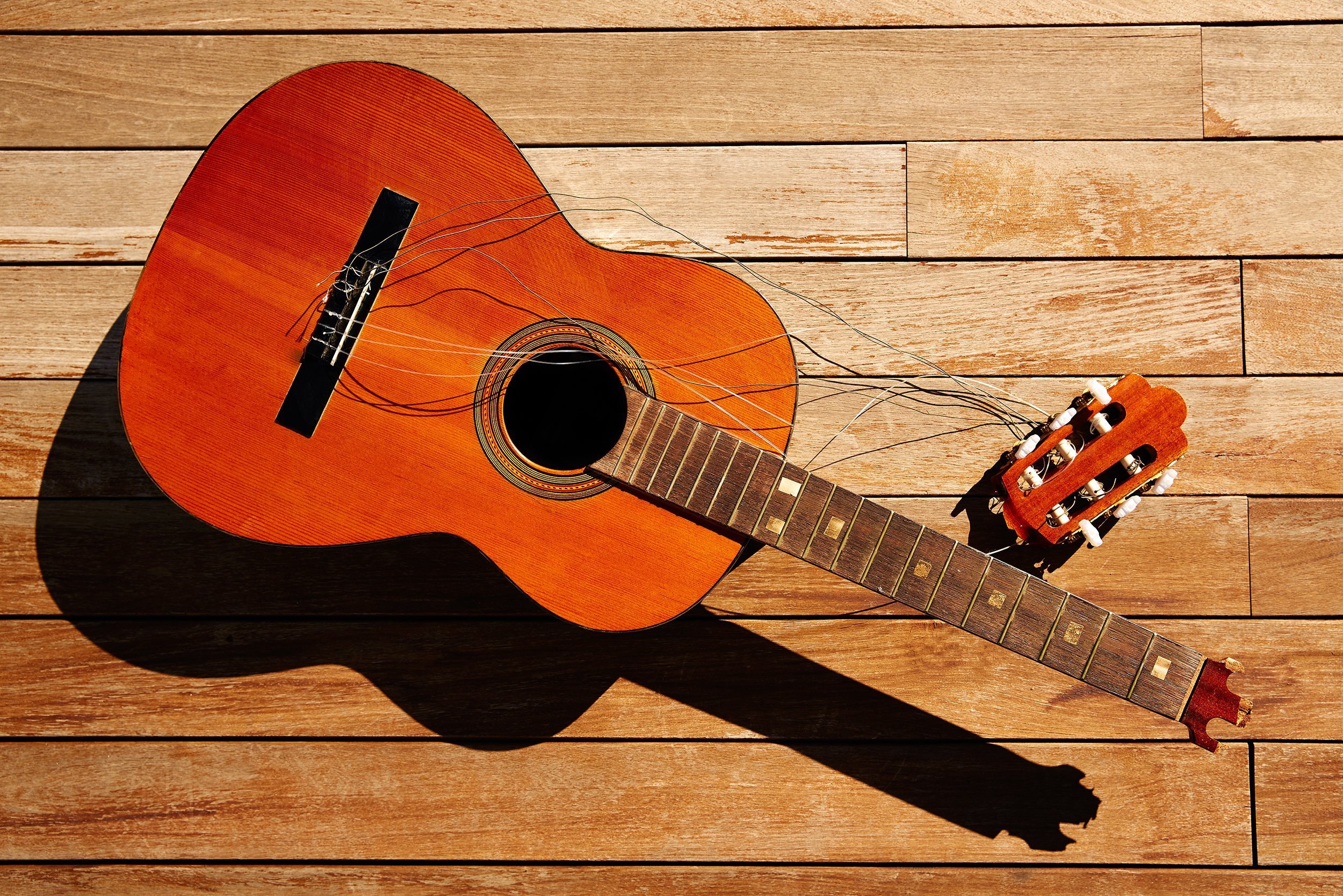 broken spanish guitar neck on the wooden deck floor