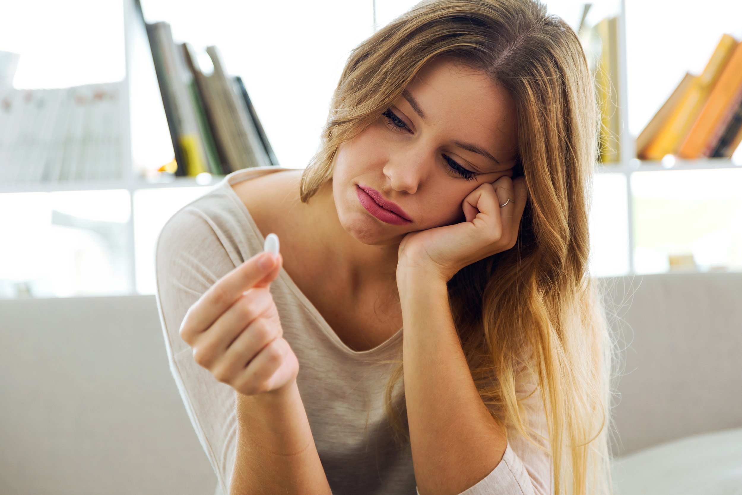 depressed young woman taking pills at home