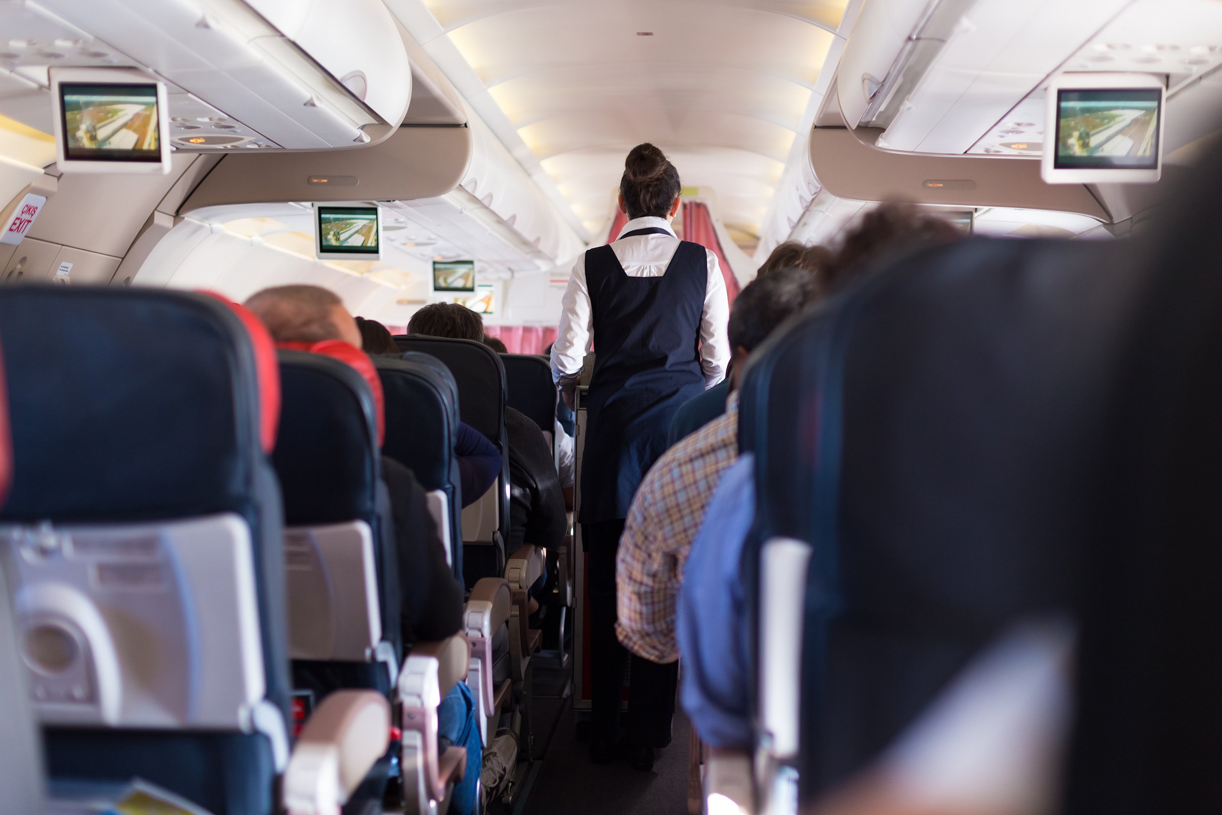 airplane with passengers on seats during flight with stewardess walking the aisle