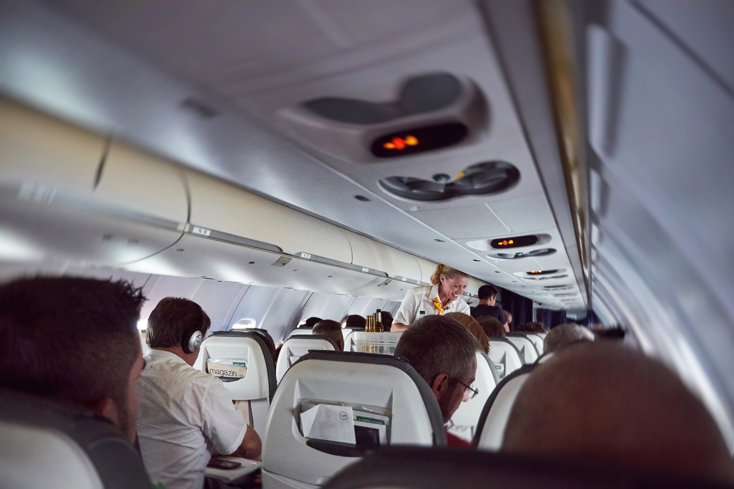 plane full with passengers with smiling stewardess serving travelers