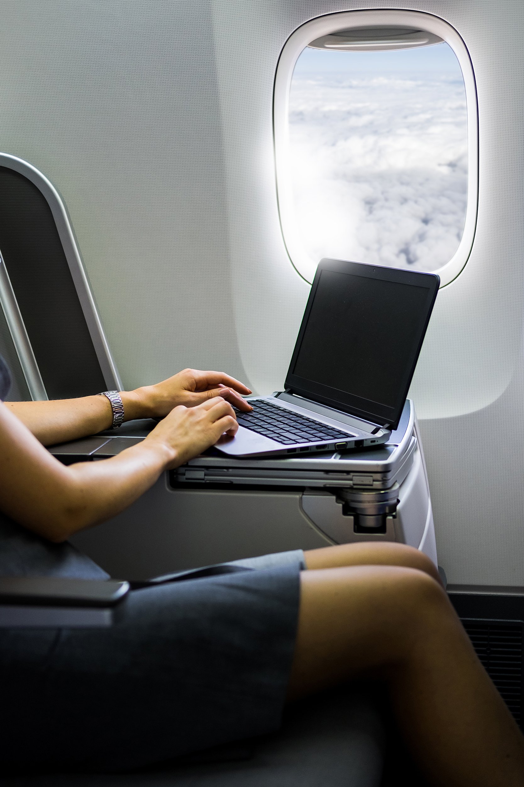 business woman hand working on laptop on airplane desk in business class cabin