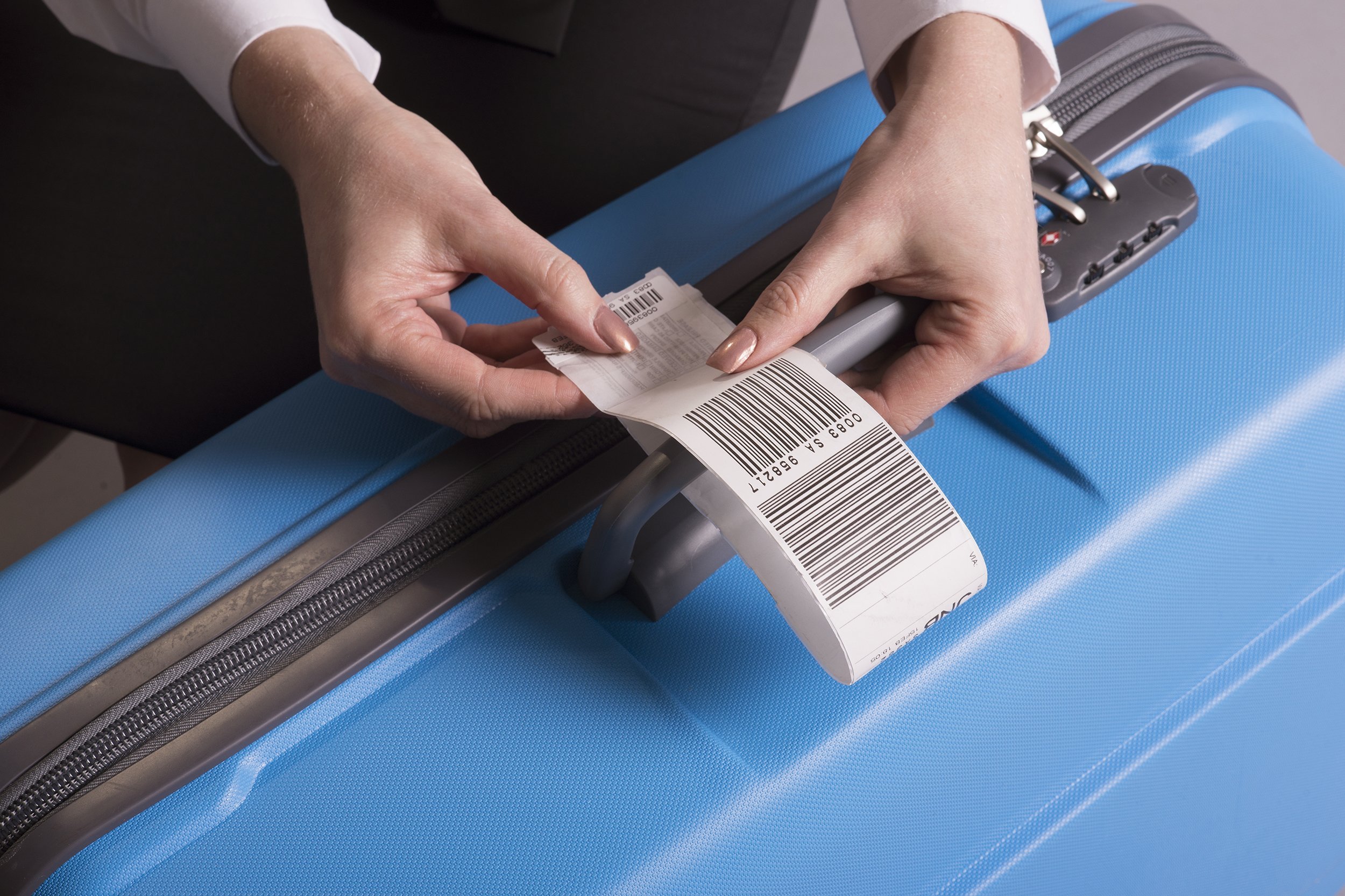 airline check in luggage tag being attached to a suitcase
