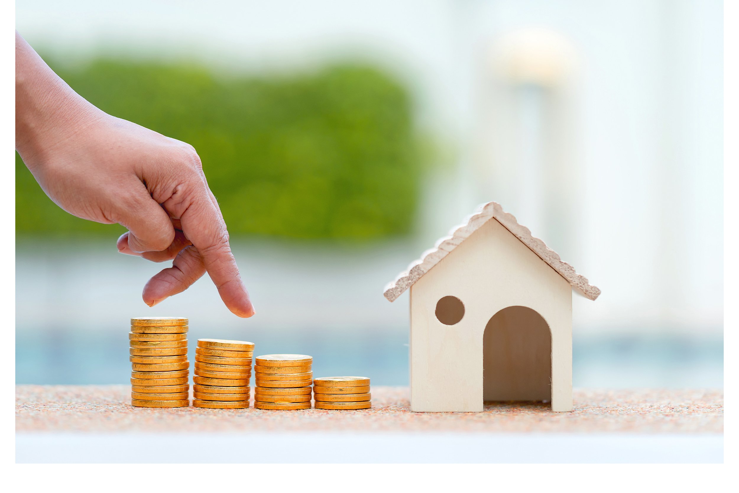 Model house with stacks of coins decreasing in cost