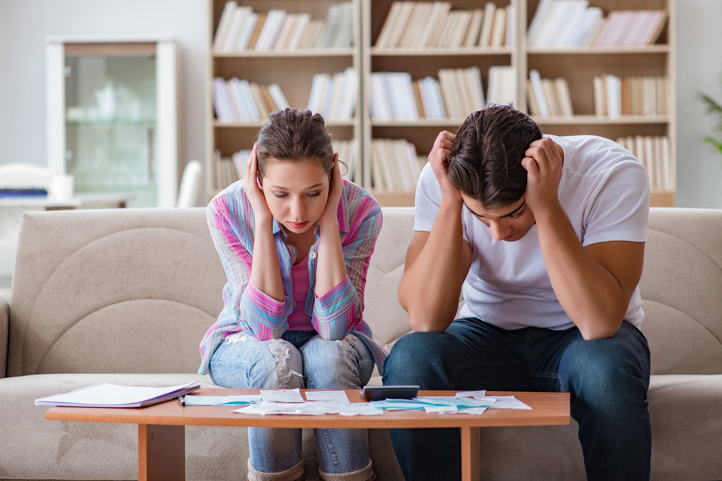 Disappointed and unhappy couple sitting on couch with heads down