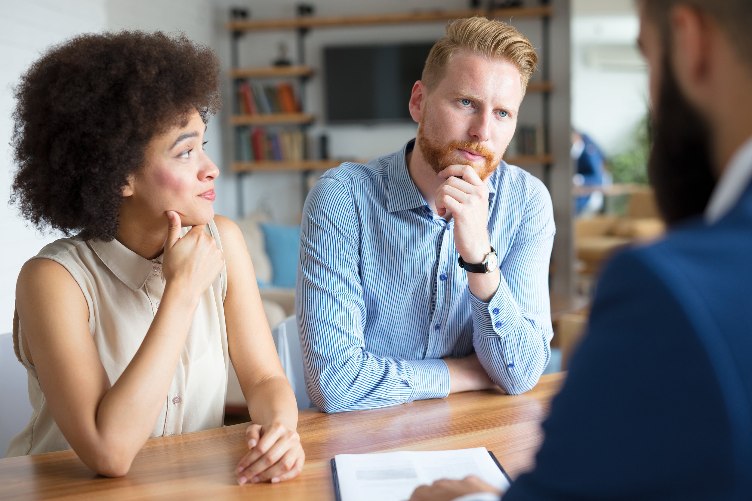 Couple looking concerned and meeting with an advisor in an office