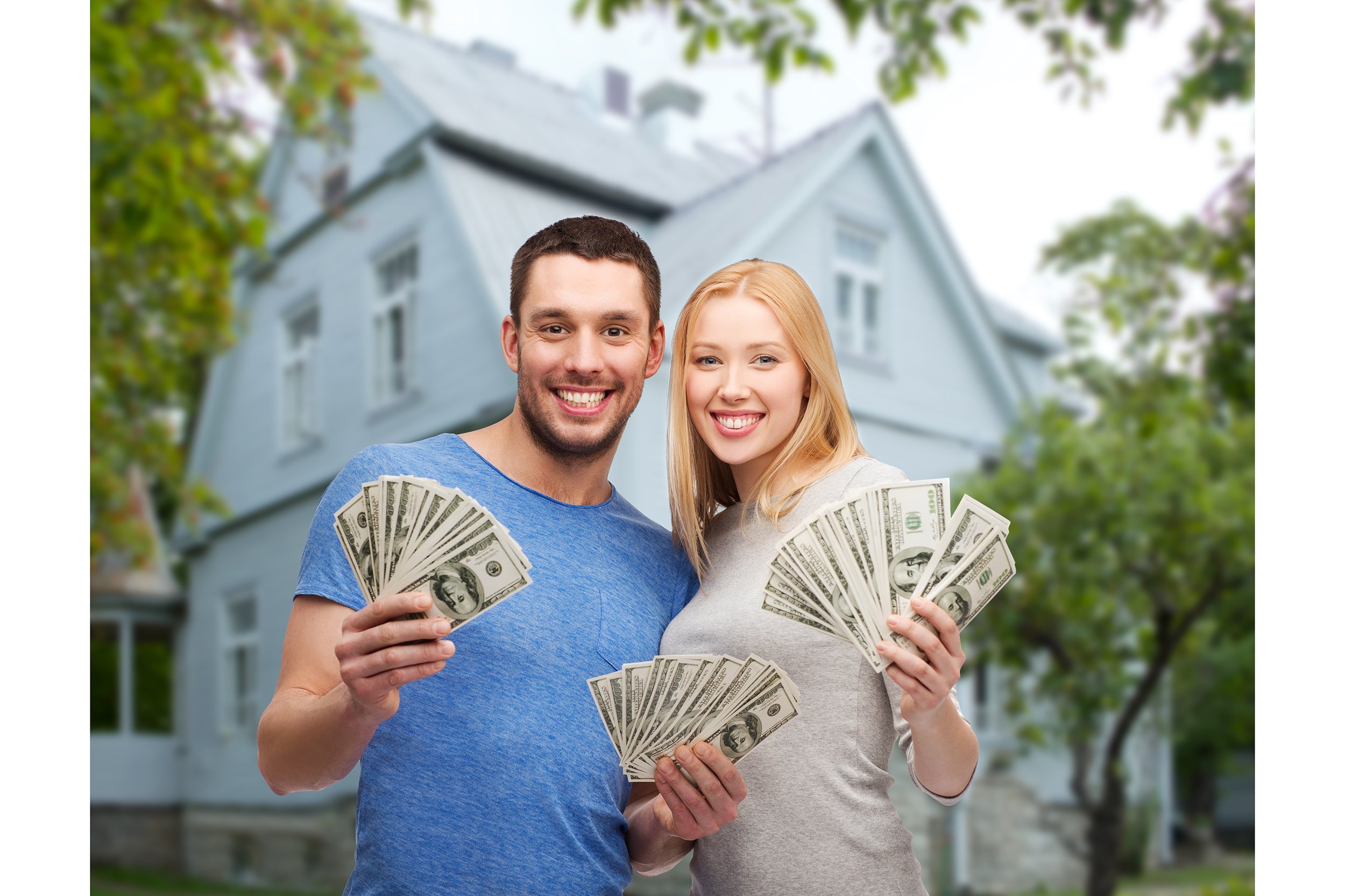 Happy couple holding cash in front of their house